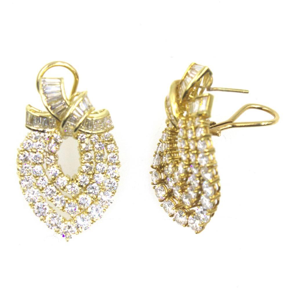 These gorgeous diamond drop earrings feature 10 carats of diamonds. The round brilliant cut and baguette cut diamonds are graded G-H color and VS clarity. Fashioned in 18 karat yellow gold, the earrings measure 1.5 inches in length and 1.0 inch in
