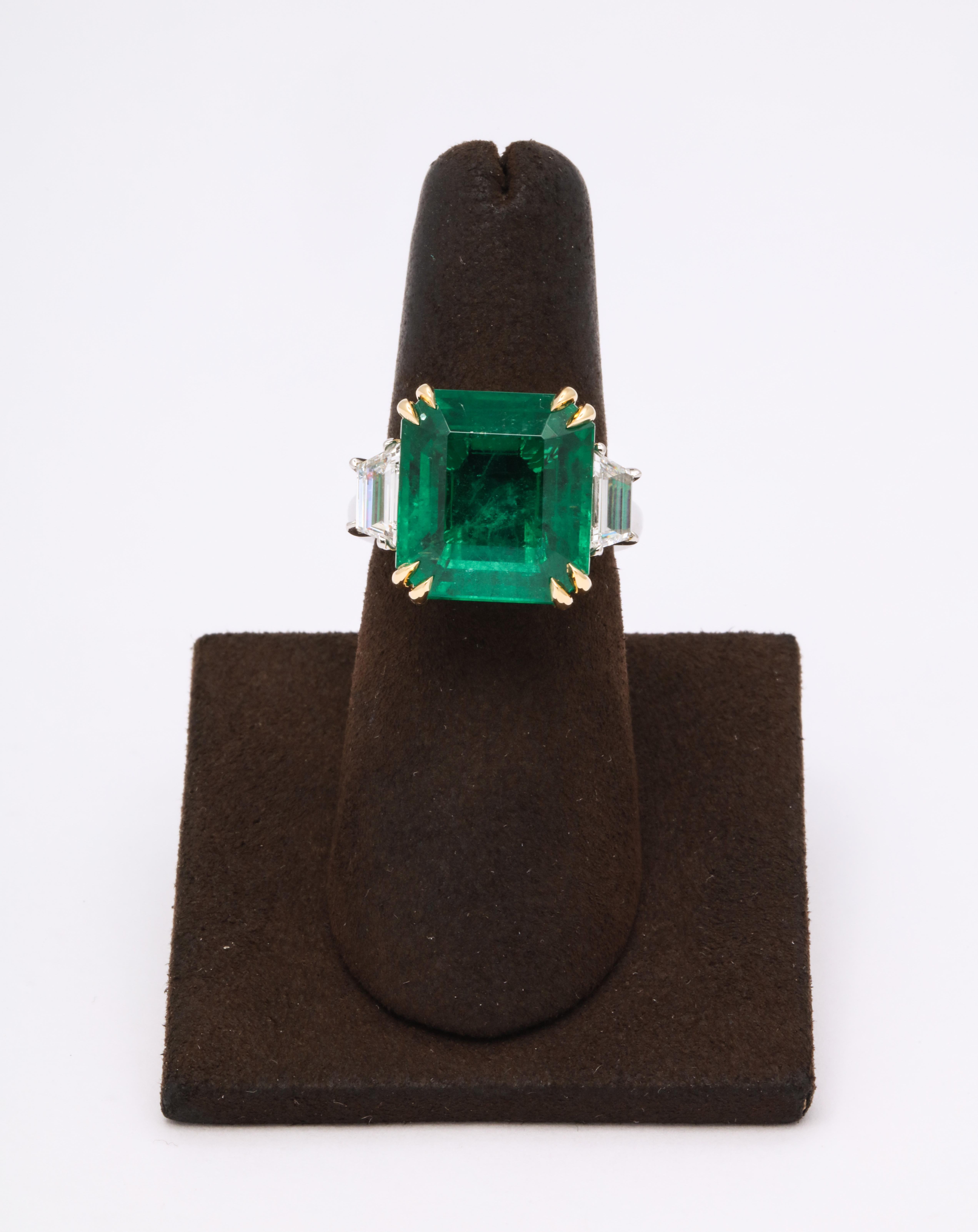 

A fine 10.73 carat VIVID GREEN Emerald set in a custom platinum and 18k yellow gold mounting with 1.16 carats of step cut trapezoid diamonds. 

The center emerald measures 14.60 mm x 13.40 mm -- it is certified by Christian Dunaigre of