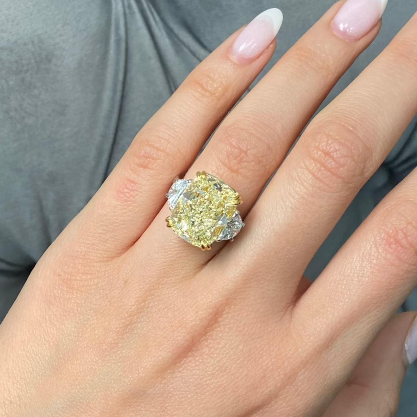 This breathtaking 10.16 carat Light Yellow diamond ring is a stunning example of rarity and craftsmanship. The elongated cushion cut center stone, in the Y-Z color range, radiates warmth and brilliance, perfectly balanced by its Very Good Excellent