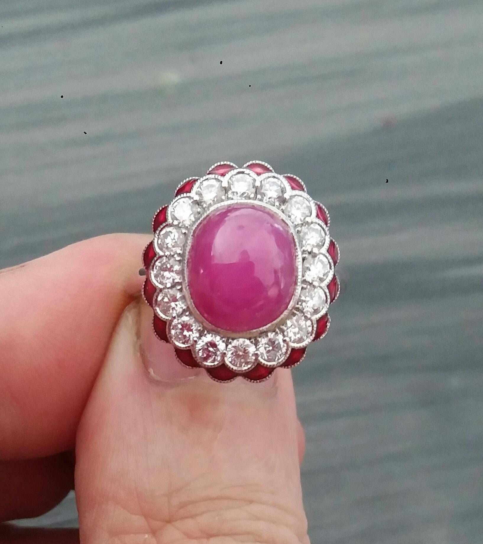 Classy Art Deco 14 White Gold Ring with a 10  Carats Oval Ruby Cabochon measuring 9x11 mm surrounded by 16 full cut brilliant cut diamonds for a total weight of 1,06 Carat...In the outer circle we have 16 little rounded triangles in red enamel
