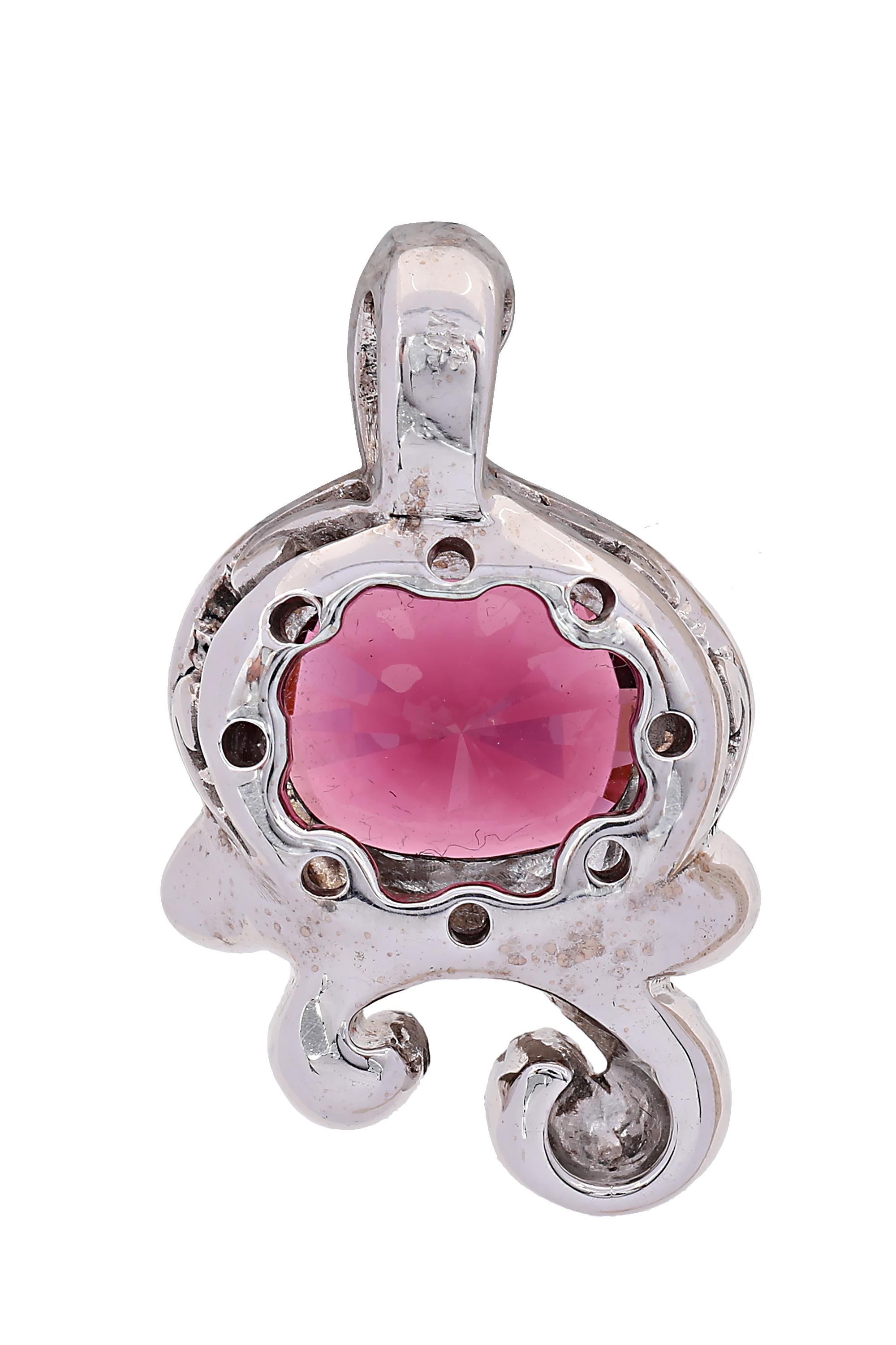 A richly saturated oval cut pink tourmaline of approximately 10 carats shines brightly from within a swirl of gleaming 14 karat white gold in this modern and very wearable pendant. Measuring 1.25