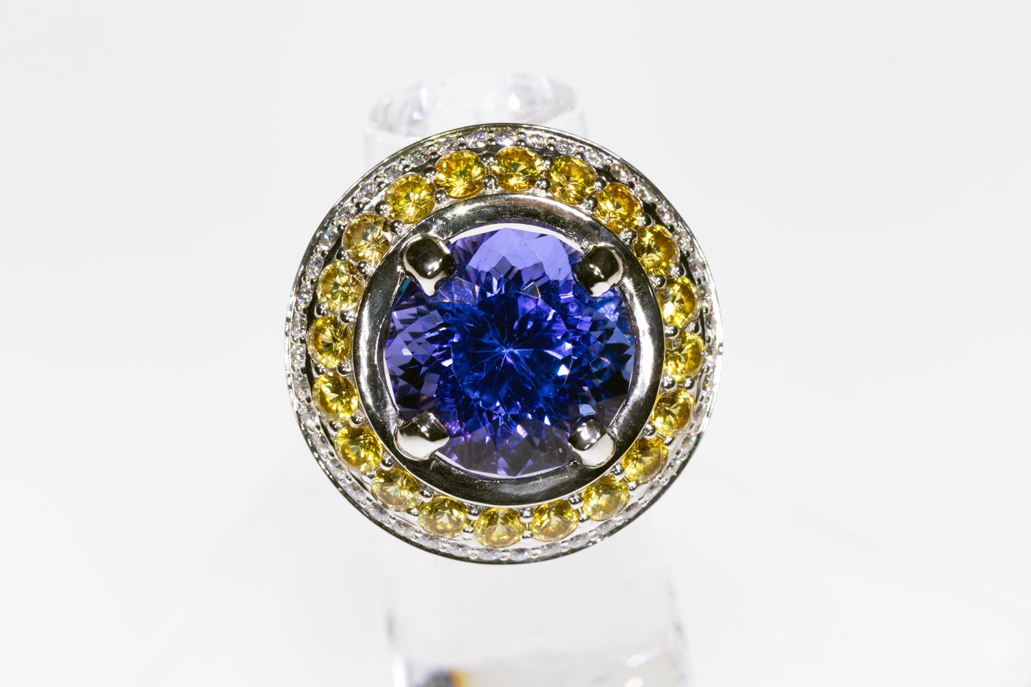 This is a one of kind beautifully crafted cocktail ring made in the studios of T Makowski Company. The ring is made from 18K White Gold and features a 10 carat Tanzanite center stone accented by natural yellow sapphires and diamonds. This is a jaw