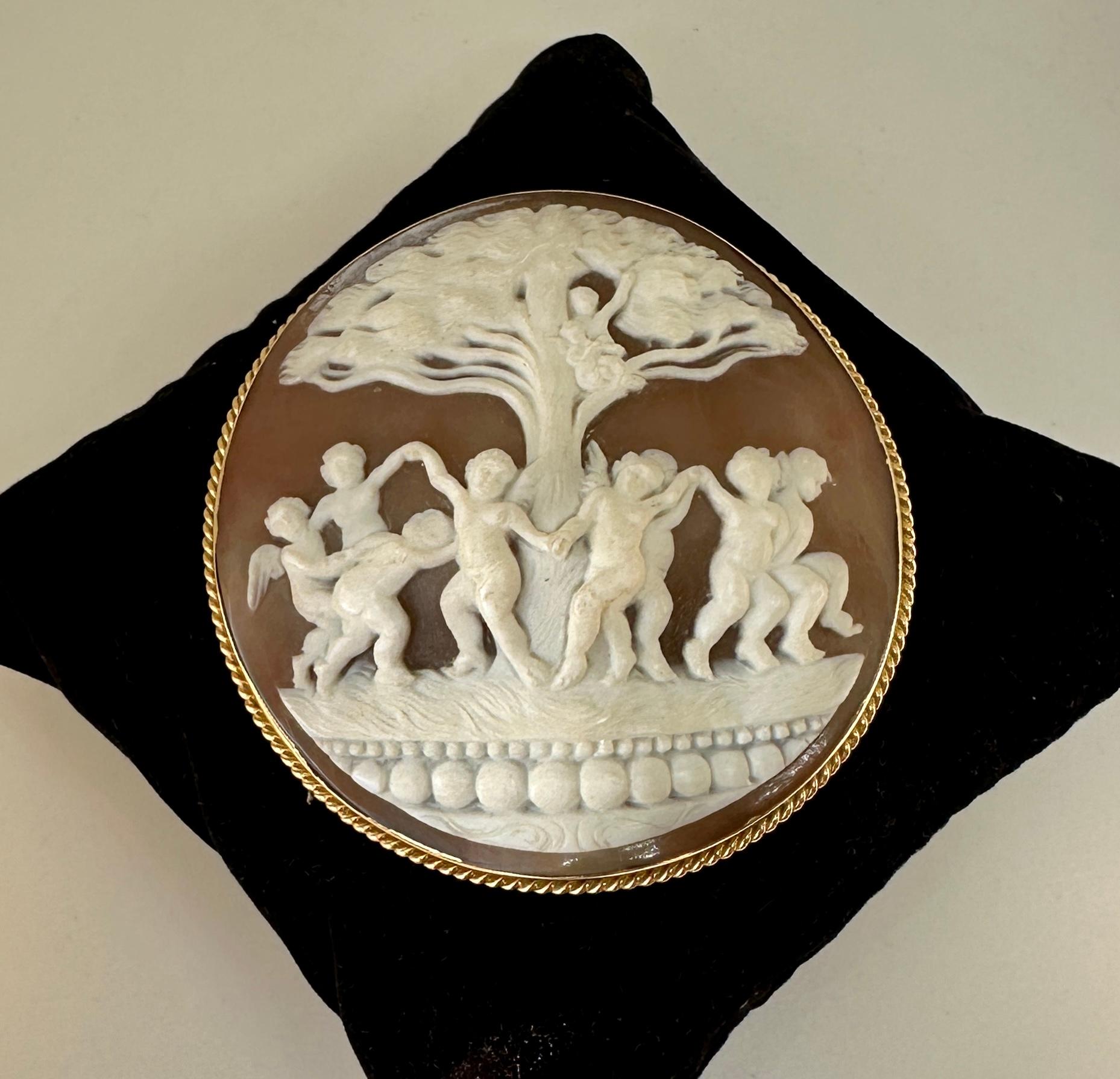 This is an absolutely stunning and very rare large 2.5 inch tall antique Shell Cameo Pendant Brooch Pin with a hand carved image of eight Cherubs, Angels, Putti, Cupids dancing around a tree with two cherubs playing instruments sitting in the tree. 