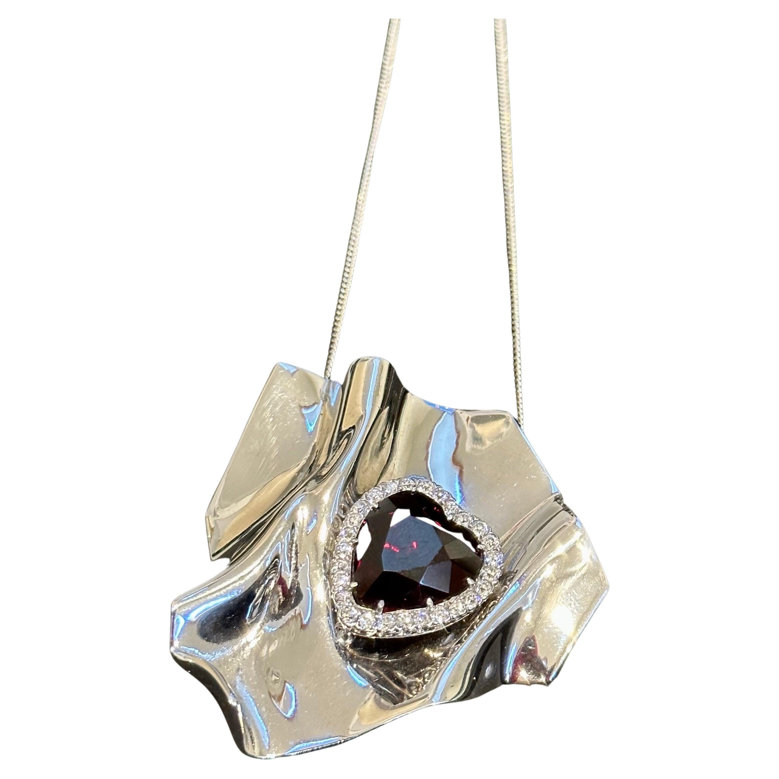 Questa collana/spilla con granato a forma di cuore da circa 10 carati e diamanti da 1,5 carati in oro bianco 14 carati è un vero capolavoro che mette in mostra l'eccezionale qualità e bellezza del granato e dei diamanti. Il pendente presenta un