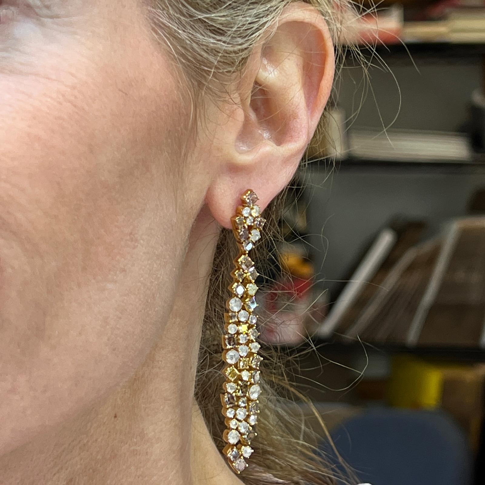 Stunning and shimmering diamond drop earrings crafted in 18 karat yellow gold. The white and champagne diamonds weigh approximately 10.00 carat total weight and are all different shapes and sizes.  The earrings measure 2.75 inches in length. 
