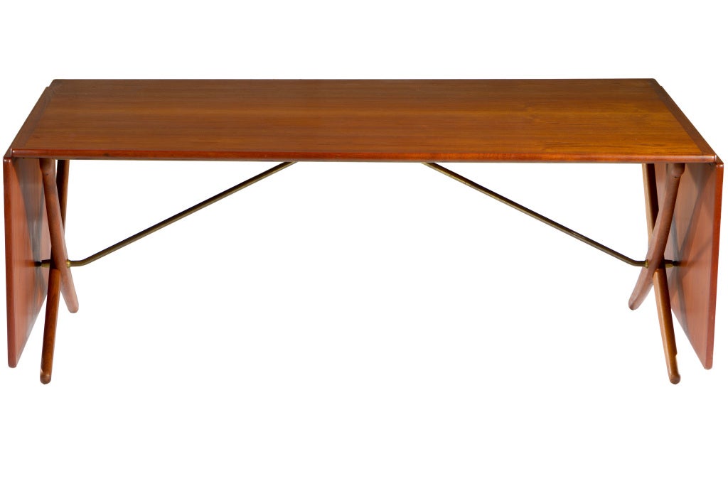 Large drop leaf dining table designed by Hans Wegner and manufactured Andreas Tuck. Denmark, 1950s. Teak top and legs with brass stretchers. Table measures 10 feet when fully extended, 76 inches when leaves are folded. Signed to bottom.