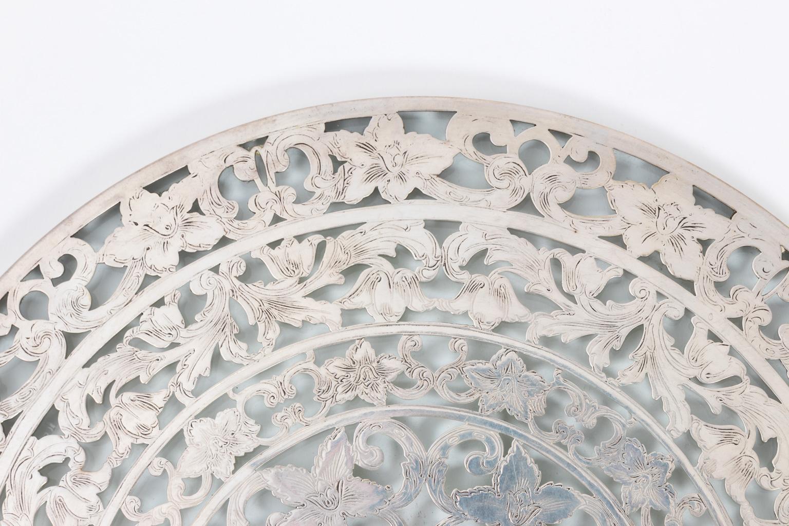 Early to mid-20th century trivet in 10 Inches diameter. The silver work is detailed with floral tracery and is marked sterling silver, Webster along with the Webster hallmark. It weighs 89.64 grams.