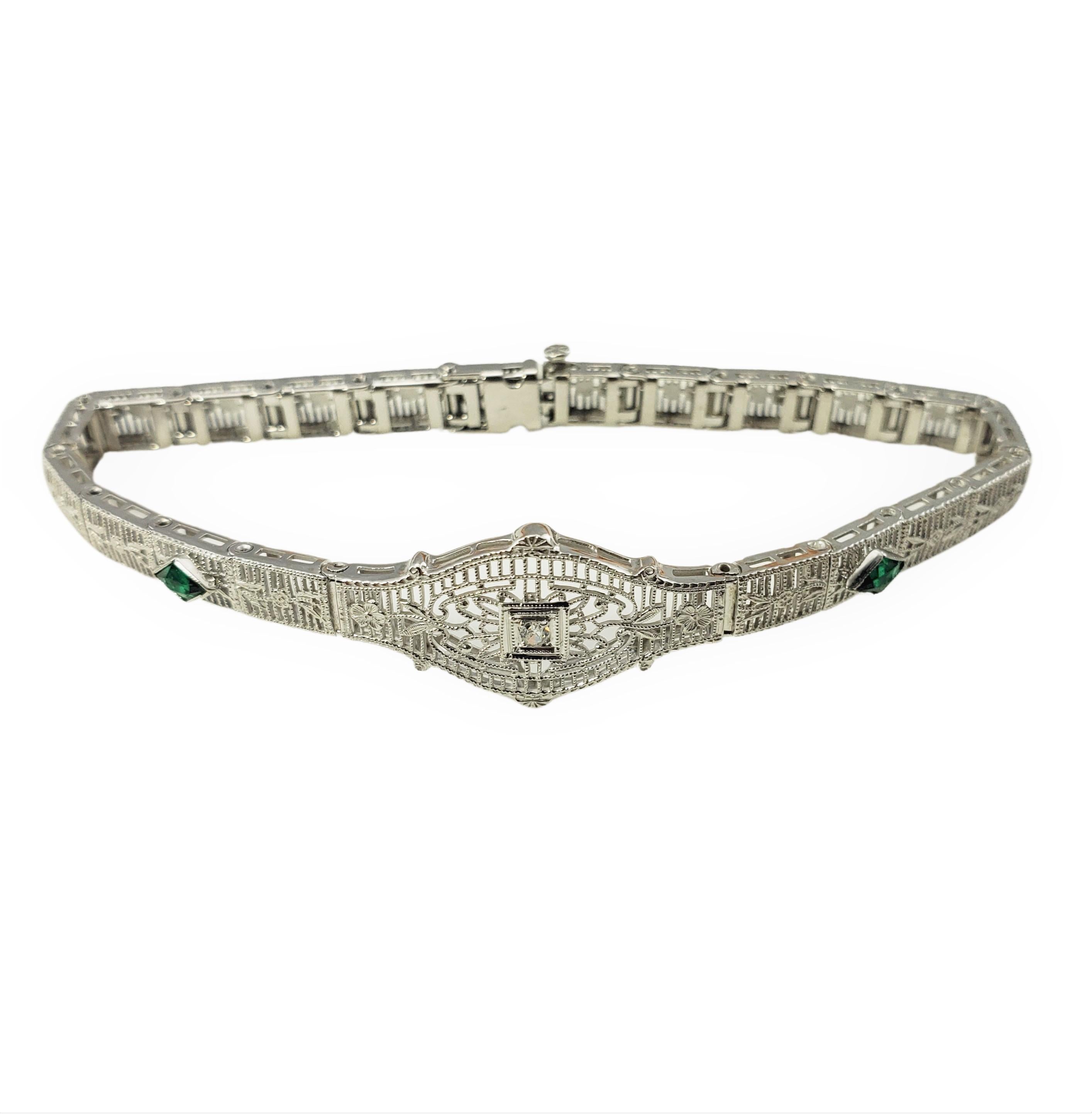 Vintage 10 Karat White Gold Filigree Diamond and Emerald Bracelet-

Ce joli bracelet présente un diamant rond taille unique d'environ 0,02 ct et deux émeraudes simulées serties dans un filigrane en or blanc 10 carats magnifiquement détaillé. 