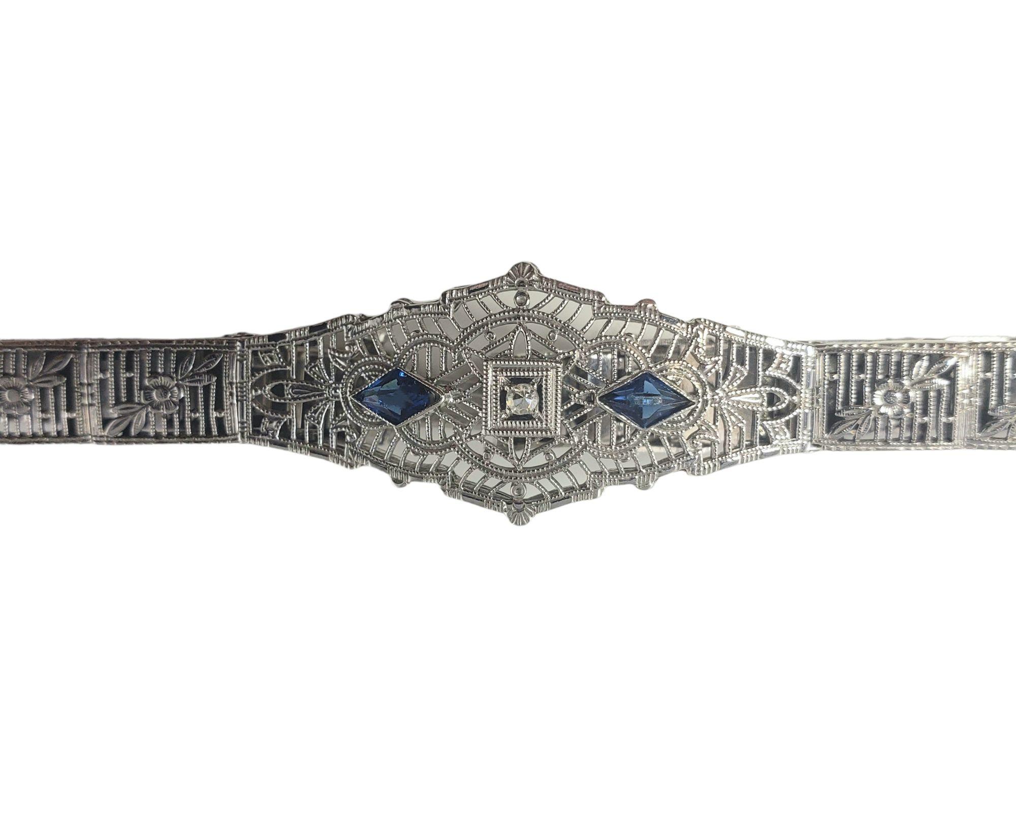Vintage 10 Karat White Gold Filigree Diamond and Blue Glass Bracelet-

This lovely bracelet features one round single cut diamond and two blue glass pieces set in beautifully detailed 10K white gold filigree. Width: 15 mm.

Approximate diamond