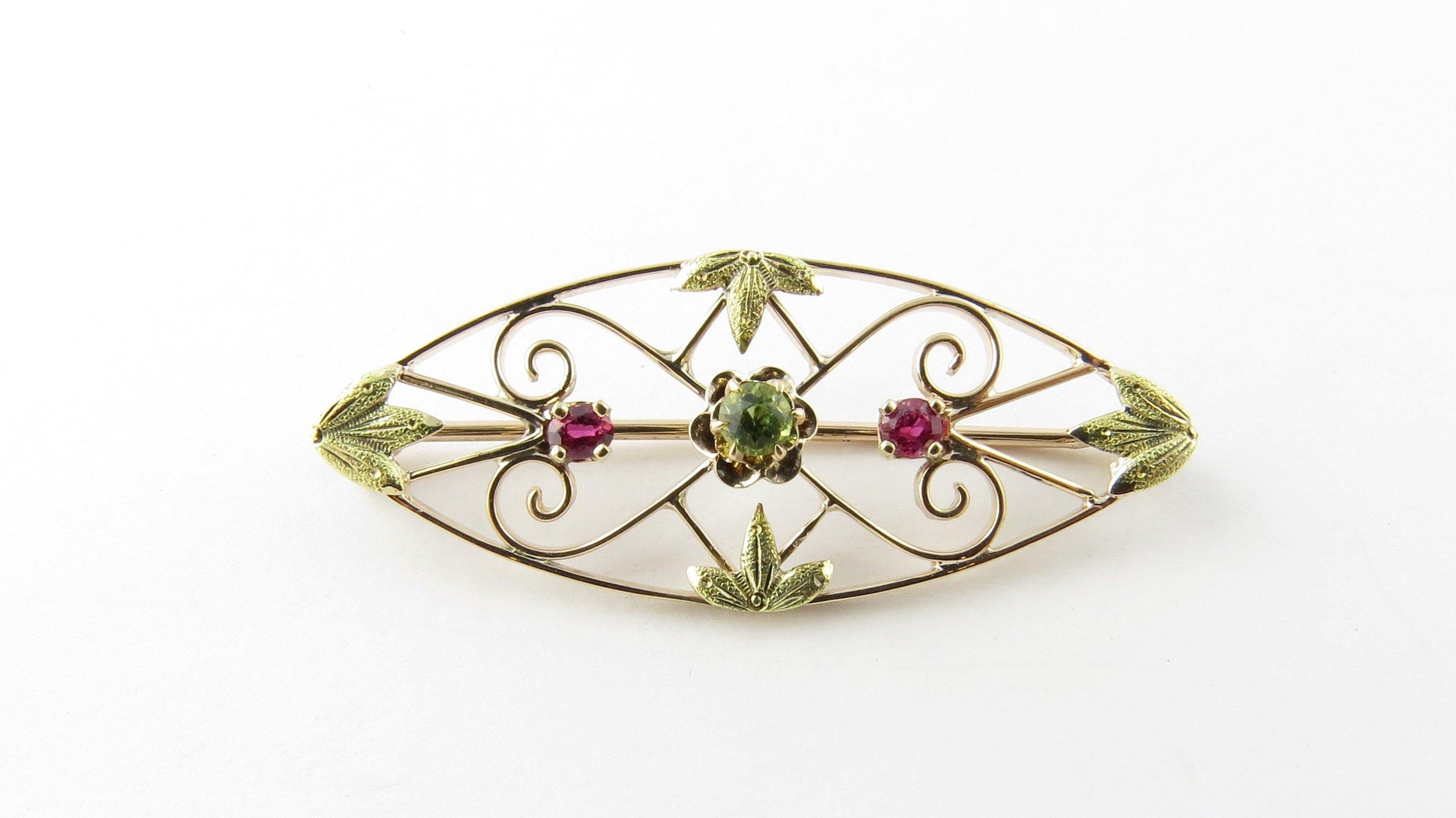 Vintage 10 Karat Yellow Gold Ruby and Peridot Brooch/Pin- 
This elegant brooch features two round rubies (3 mm each) and one round peridot (4 mm) set in delicate yellow gold filigree. 
Size: 13 mm x 34 mm 
Weight: 1.2 dwt. / 2.0 gr. 
Stamped 10K