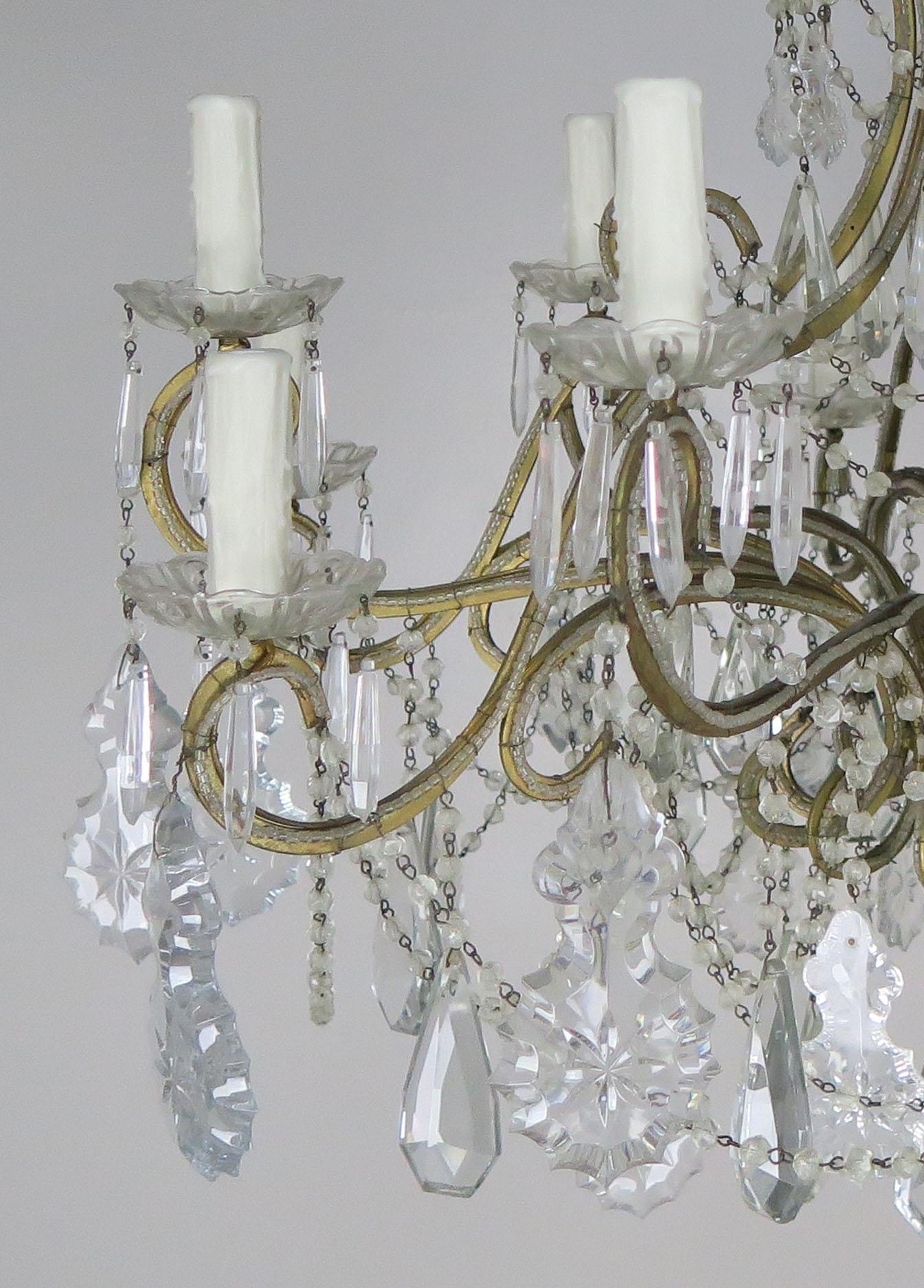 10-light French Louis XV style crystal beaded chandelier, circa 1930s. The chandelier is adorned with etched cut pendulum shaped crystals and garlands of English cut beads throughout. The fixture is newly rewired with drip wax candle covers and