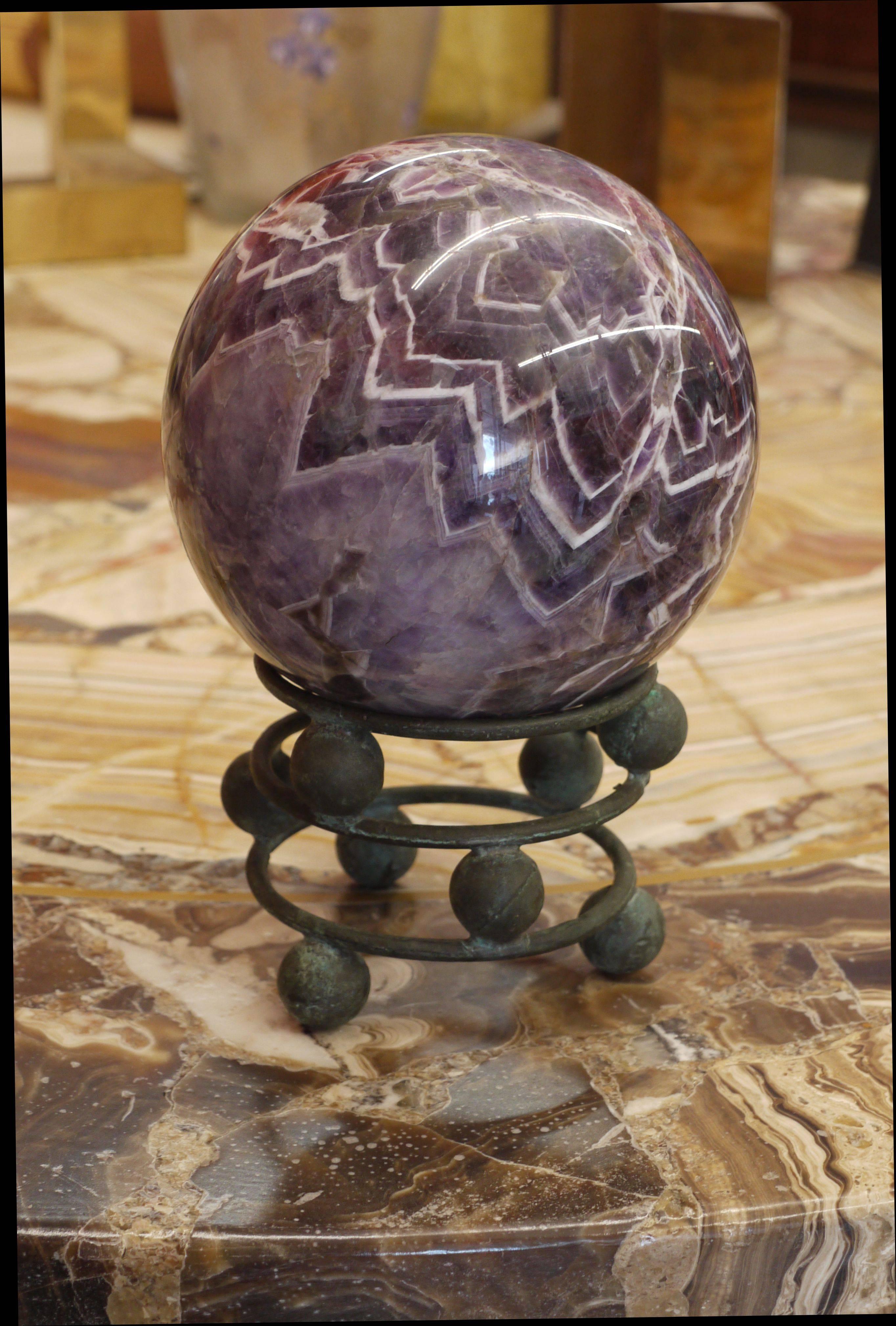 Large 5.5 inch polished amethyst sphere with incredible pattern sitting on top of a vintgae bronze stand made of spheres and rings. The stand almost looks like the whole thing is balancing. Amazing construction of the stand as it seems as it's all