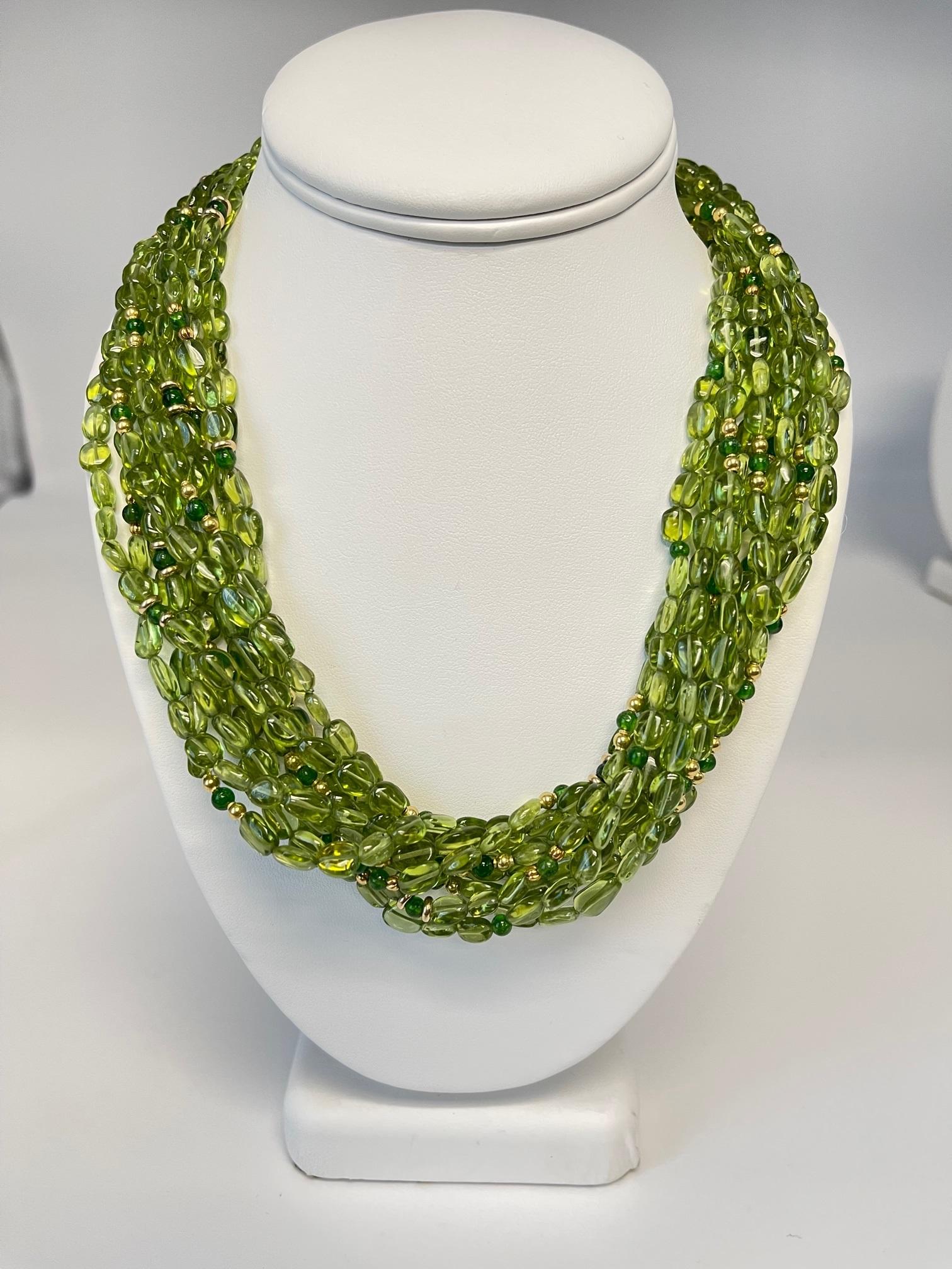 Cet impressionnant collier torsade est composé de 10 brins individuels de perles ovales de péridot de forme libre, enfilées à la main sur un fil de soie vert et agrémentées d'entretoises en or jaune 18 carats et de perles rondes en diopside chromé !