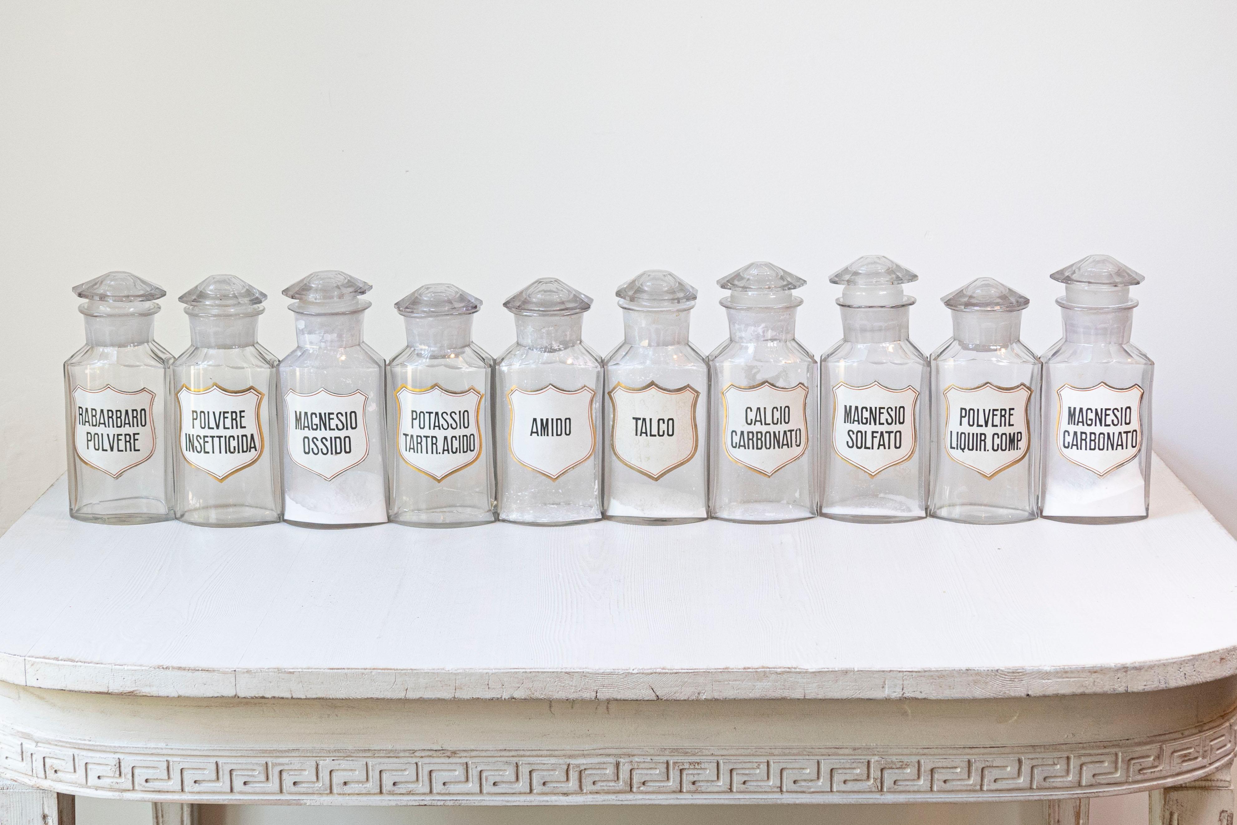 This set of 10 vintage Italian glass pharmacy jars embodies the charm of classic apothecary design. Each jar is crafted from clear glass with an elegant hexagonal shape, topped with matching glass stoppers that provide both aesthetic appeal and