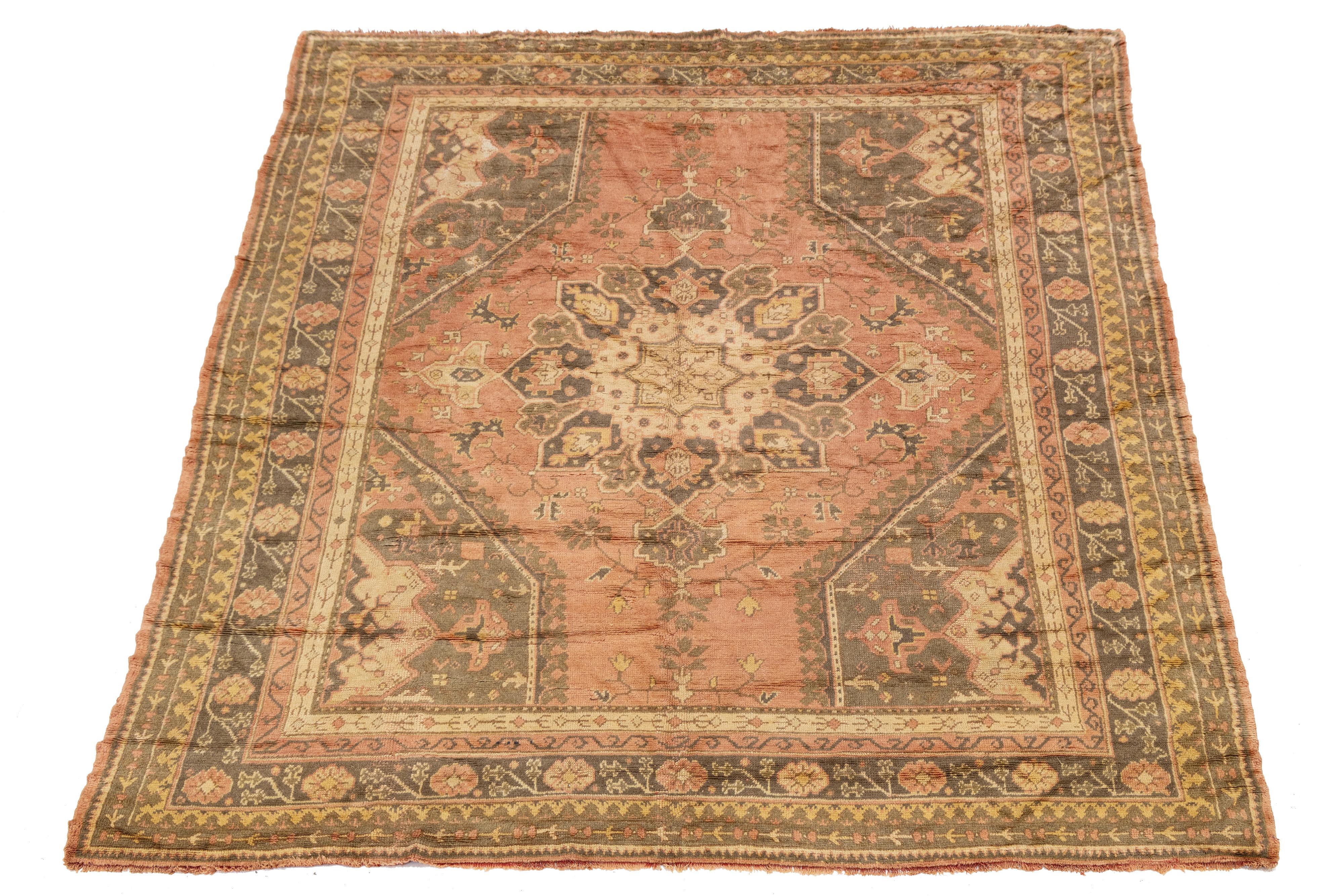 Antique Oushak wool rug featuring a luminous patina and soft, earthy tones. Handwoven with large-scale floral motifs and a spacious medallion design, this piece showcases the elegance of early 20th-century craftsmanship. Ideal for collectors and