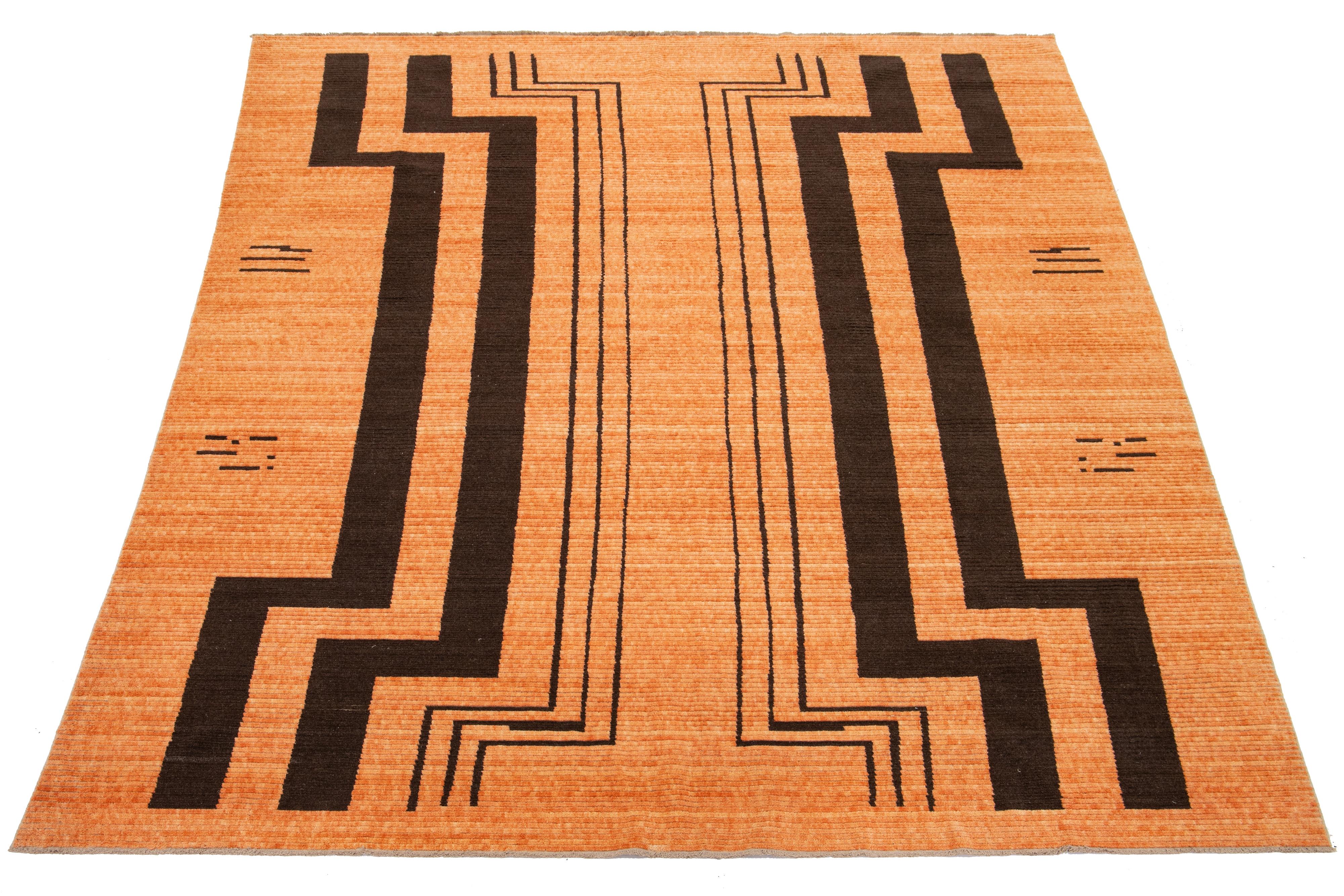 Dieser handgewebte moderne Wollteppich ist ein wahrer Blickfang. Der leuchtend orangefarbene Hintergrund ist die perfekte Leinwand für das komplizierte geometrische Muster in sattem Braun und verleiht jedem Raum eine auffallende optische