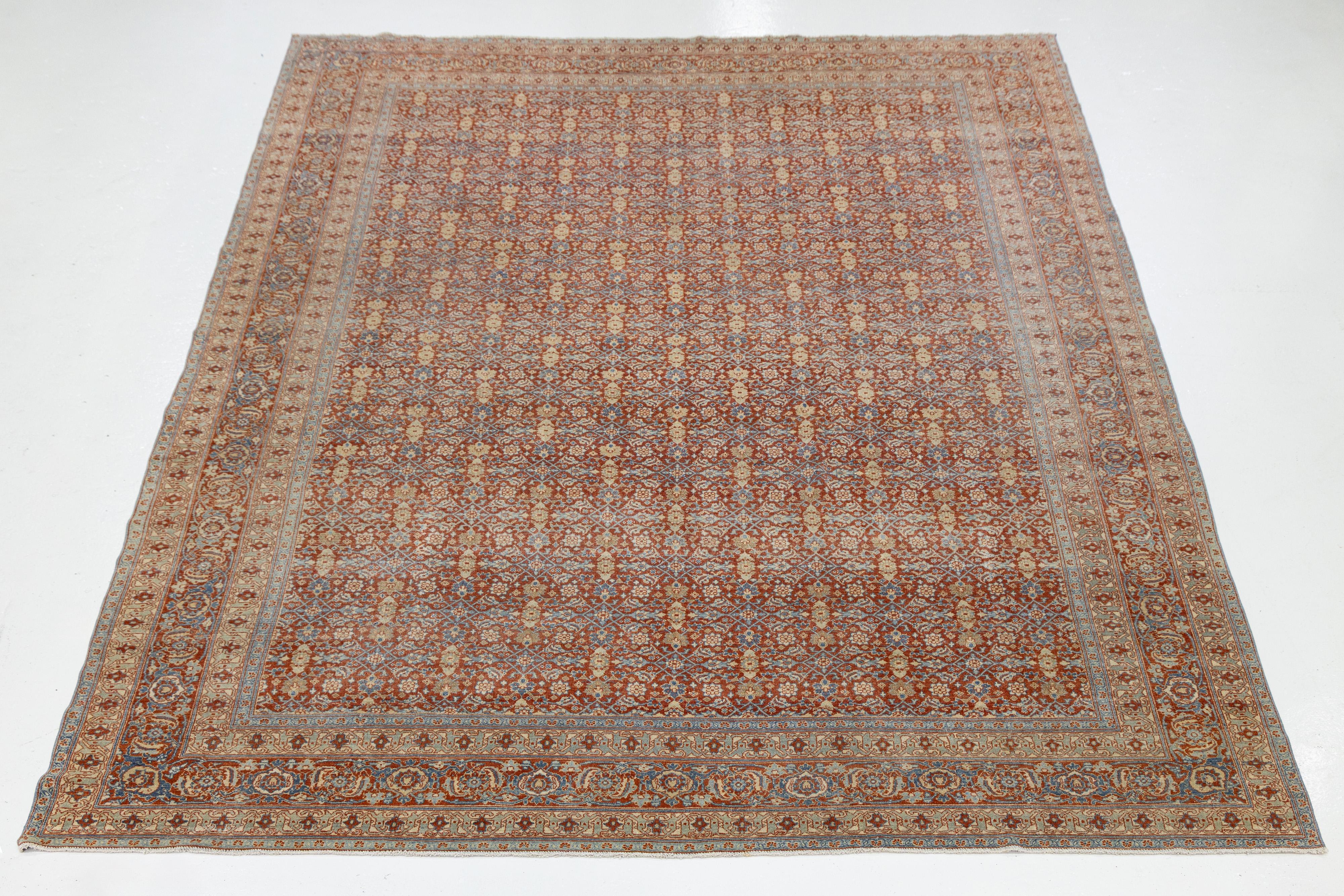 Beautiful antique Tabriz hand-knotted wool rug with a red field. This piece features a designed frame with beige and blue accent colors, set against a gorgeous all-over classic floral design.

This rug measures 9'8