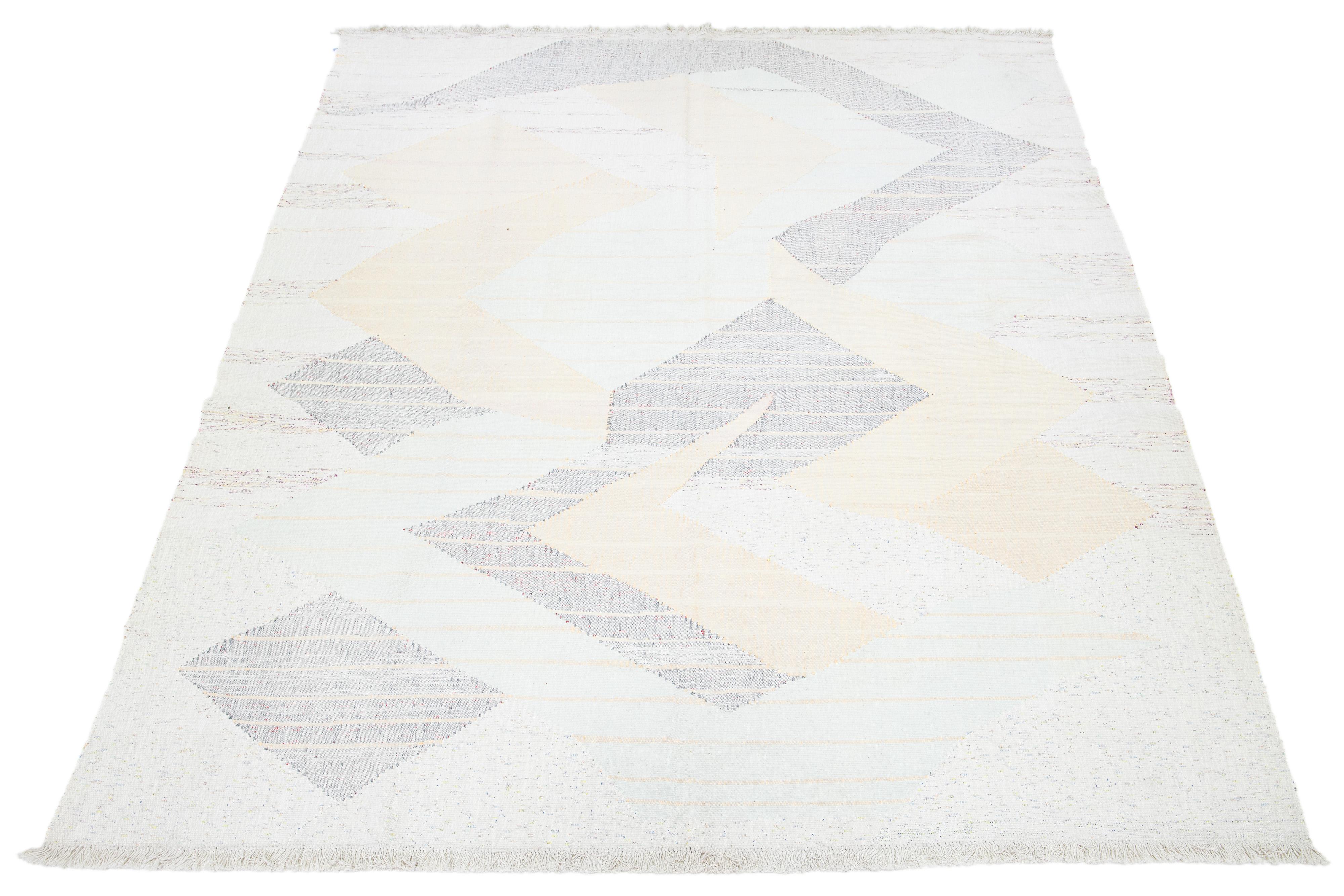 Dieser Teppich zeigt ein modernes Flachgewebe im Kilim-Stil, das aus Wolle gefertigt ist. Es hat ein beiges Feld mit einem abstrakten Motiv in Pfirsich- und Grautönen.

Dieser Teppich misst 9'7