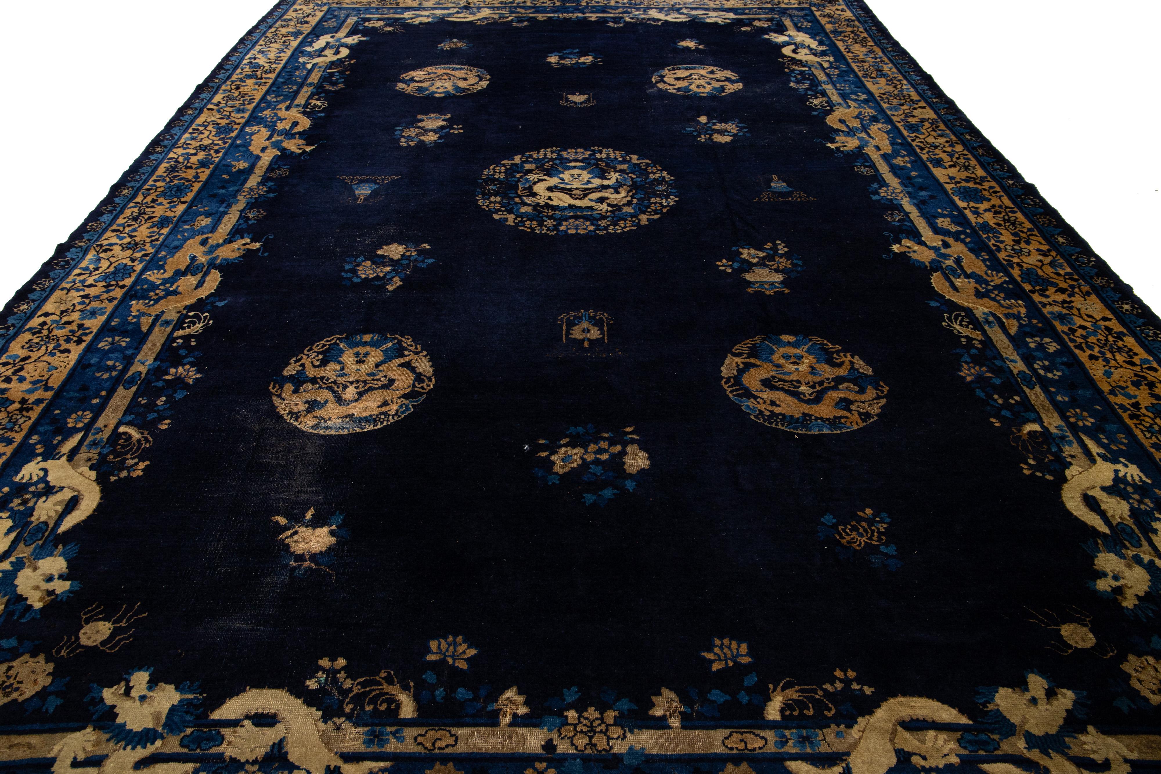 Esta extraordinaria alfombra antigua de estilo Art Déco chino está expertamente anudada a mano con lana de alta calidad. Presenta un fondo azul oscuro adornado con un elegante diseño floral en beige, cuidadosamente enmarcado por un ribete a juego en
