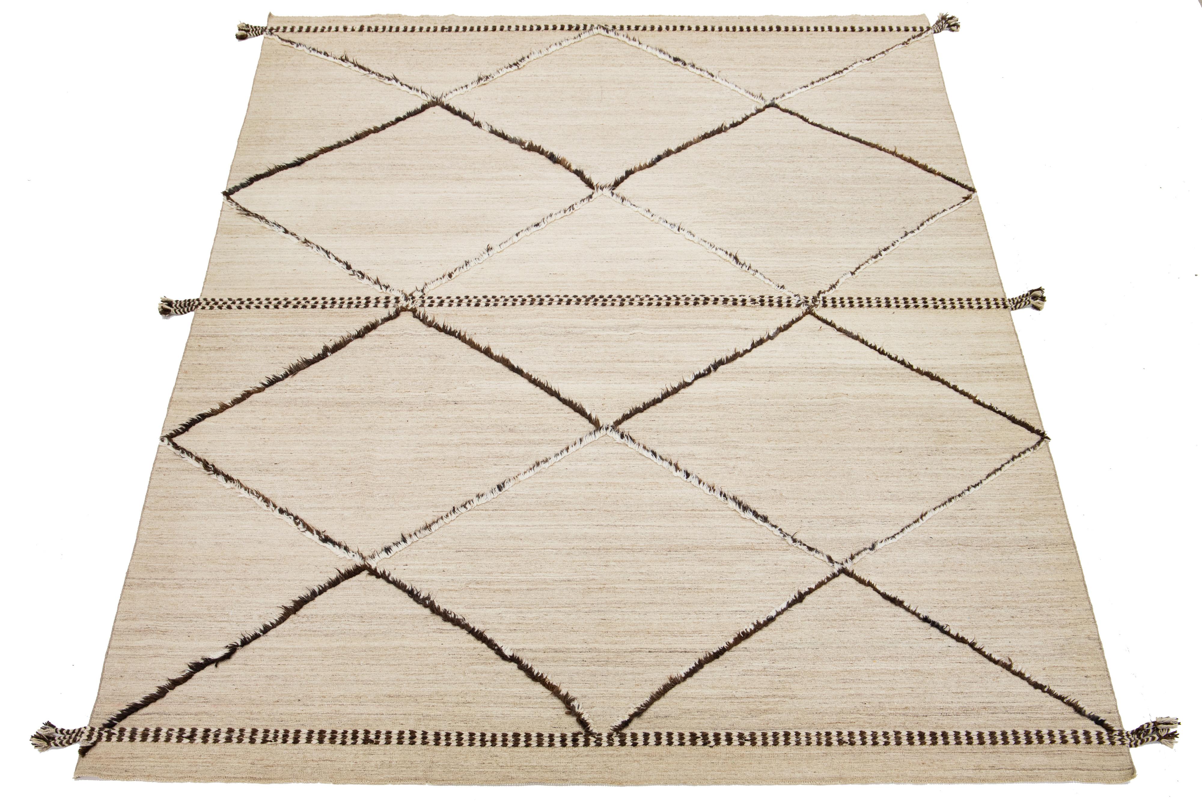 Questo tappeto in lana in stile marocchino, realizzato a mano e in stile contemporaneo, presenta uno splendido sfondo beige e marrone chiaro che fonde perfettamente l'artigianato tradizionale con elementi di design moderno nelle tonalità del