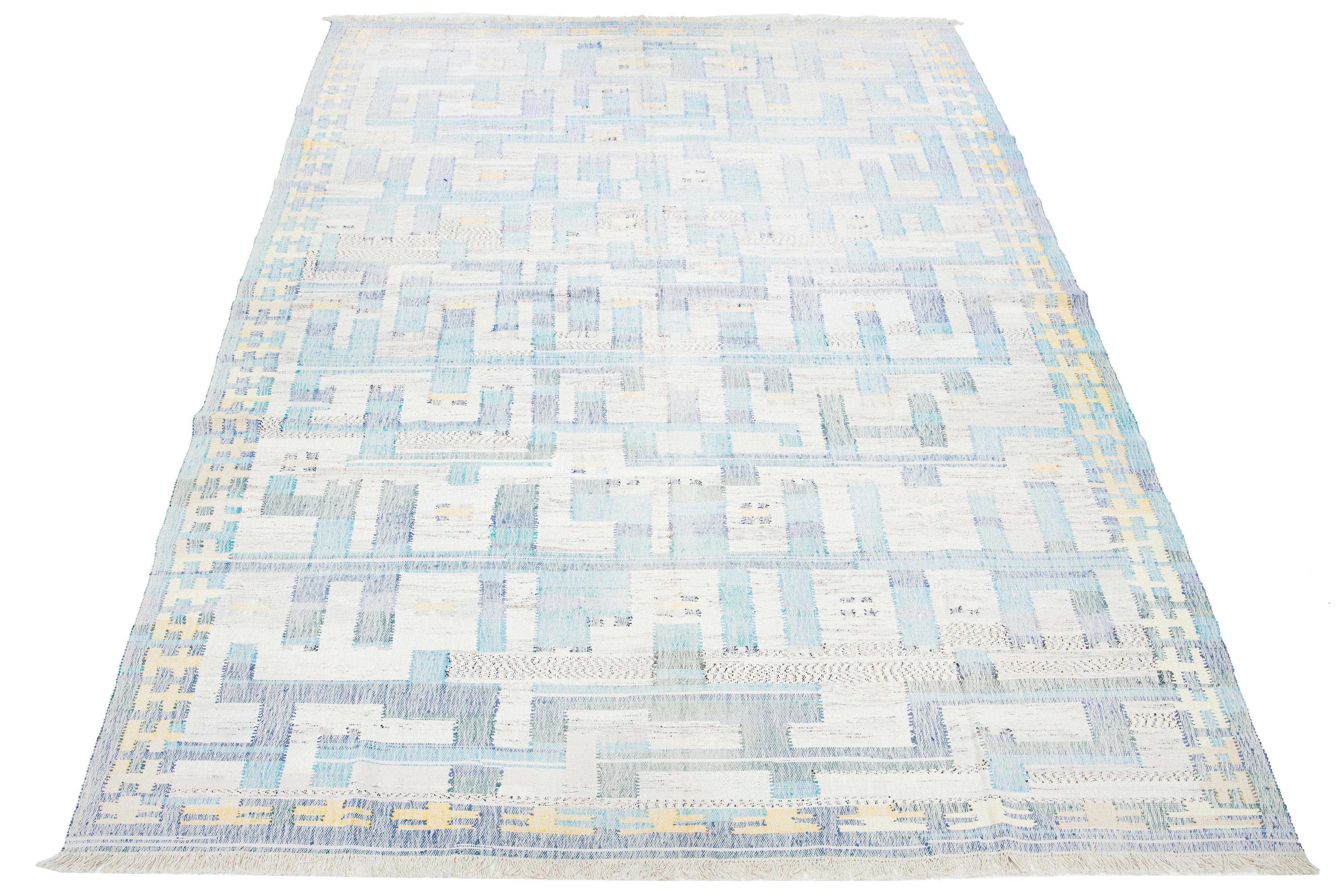 This rug showcases a contemporary Kilim flatweave pattern crafted from wool. It features a beige base with an abstract blue, purple, and yellow motif.

This rug measures 10' x 16'.


