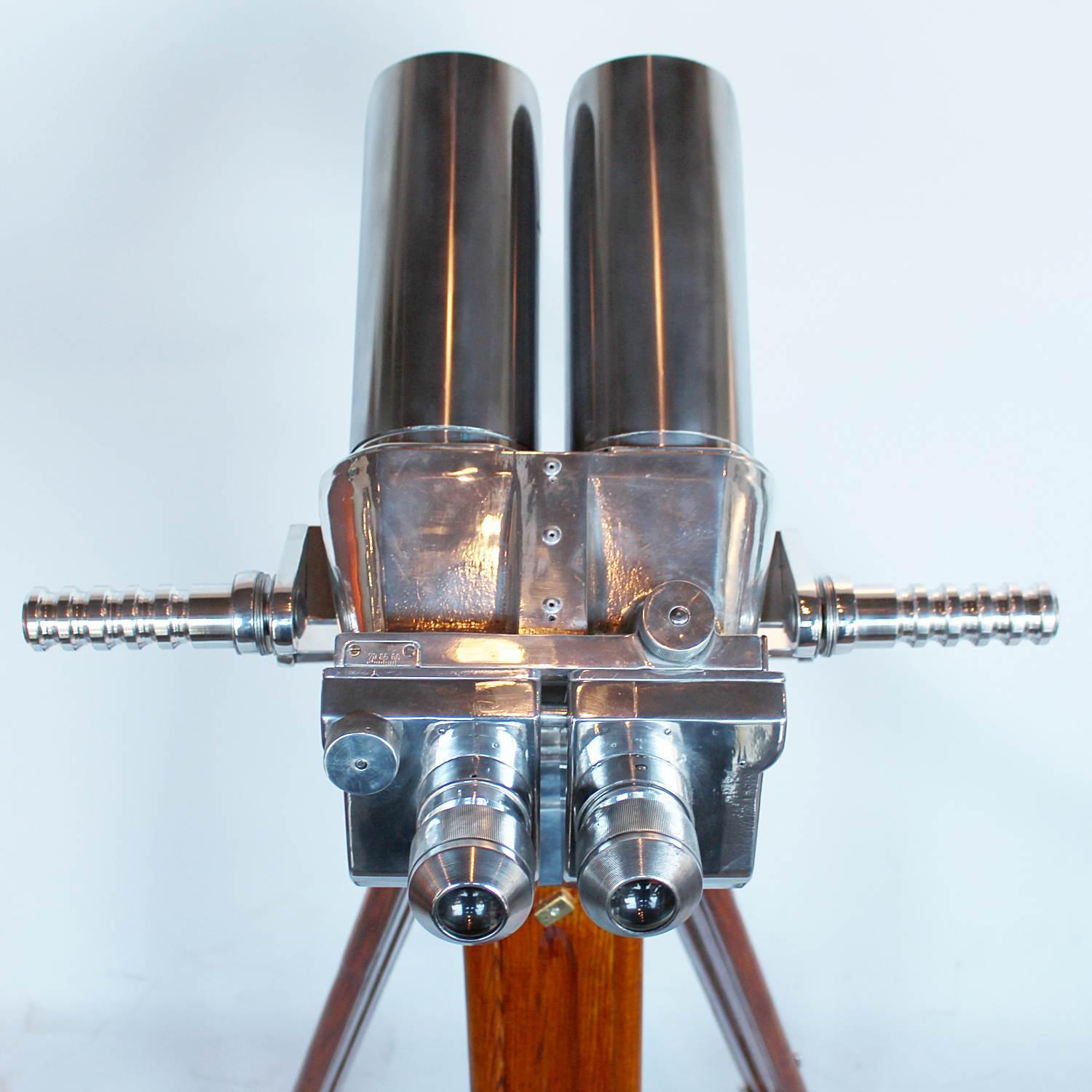 A pair of 10x80 binoculars with eyepieces set at 45 degrees, attributed to Zeiss. Set on period, extending oak and brass stand with chromed conical feet. 10 times magnification with 80mm objective lens.

Paint stripped and metal polished. Fully