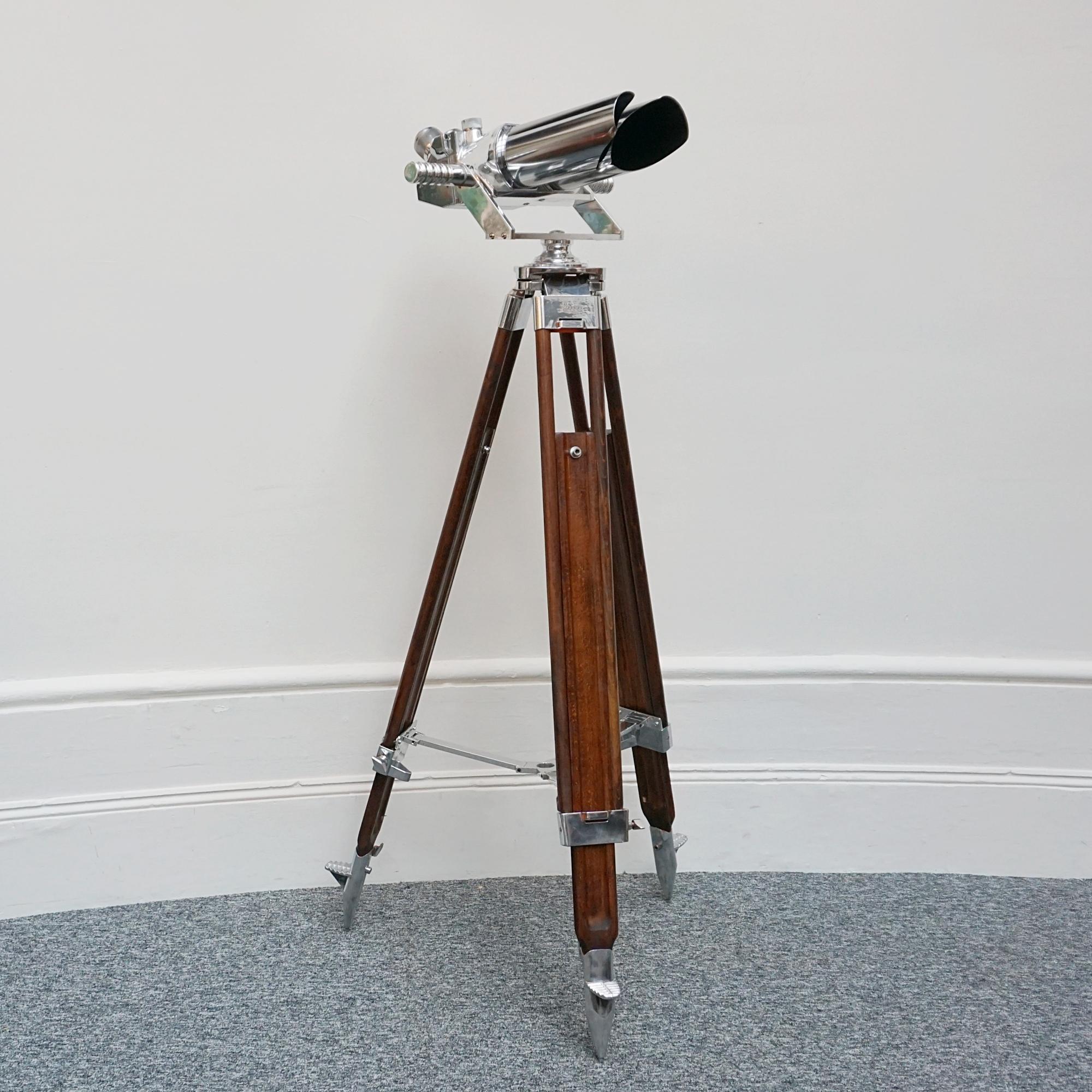 A pair of 10x80 observation binoculars designed by Emil Busch Optical Industries of Rathenow. WW11 naval binoculars with eyepieces set at 45 degrees. Set on a later extending wood and chromed metal stand, with chromed conical feet. This design was