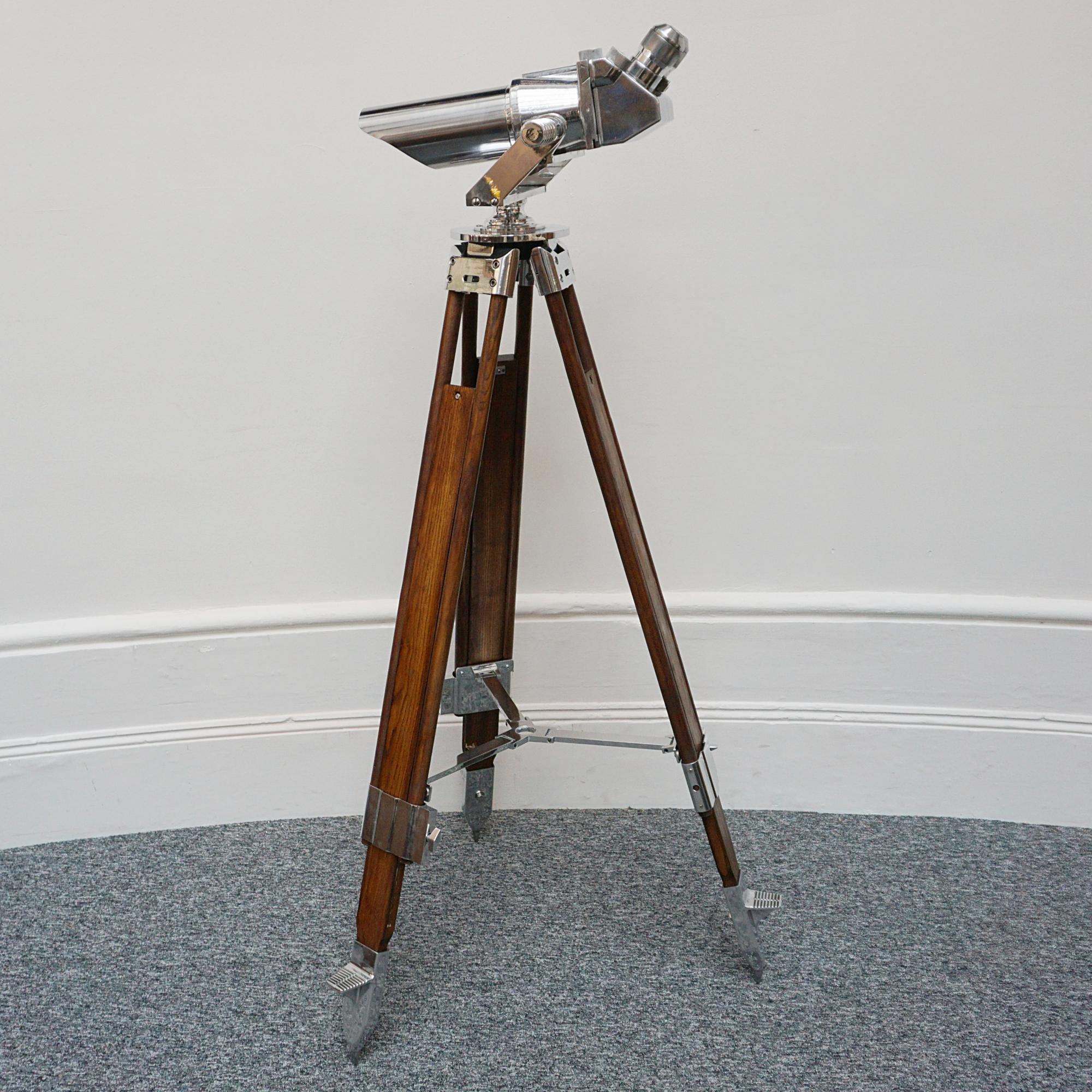 A pair of 10x80 observation binoculars designed by Emil Busch Optical Industries of Rathenow. WW11 naval binoculars with eyepieces set at 45 degrees. Set on a later extending wood and chromed metal stand, with chromed conical feet. This design was