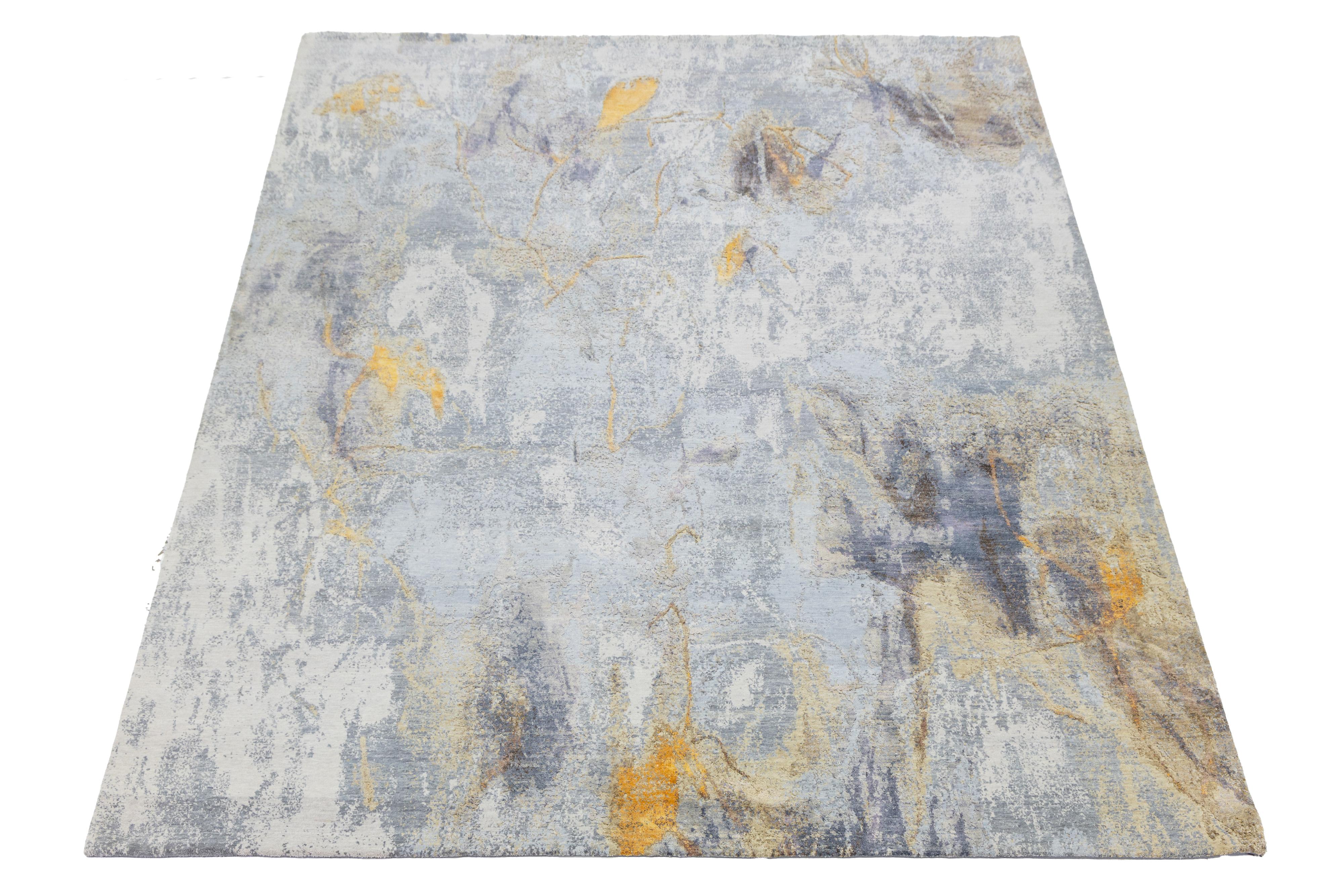 Questo tappeto contemporaneo annodato a mano vanta un sorprendente disegno astratto e una palette di colori vivaci. Realizzato in lana o seta di alta qualità, presenta uno sfondo grigio, beige e oro che mette in risalto il motivo intricato,