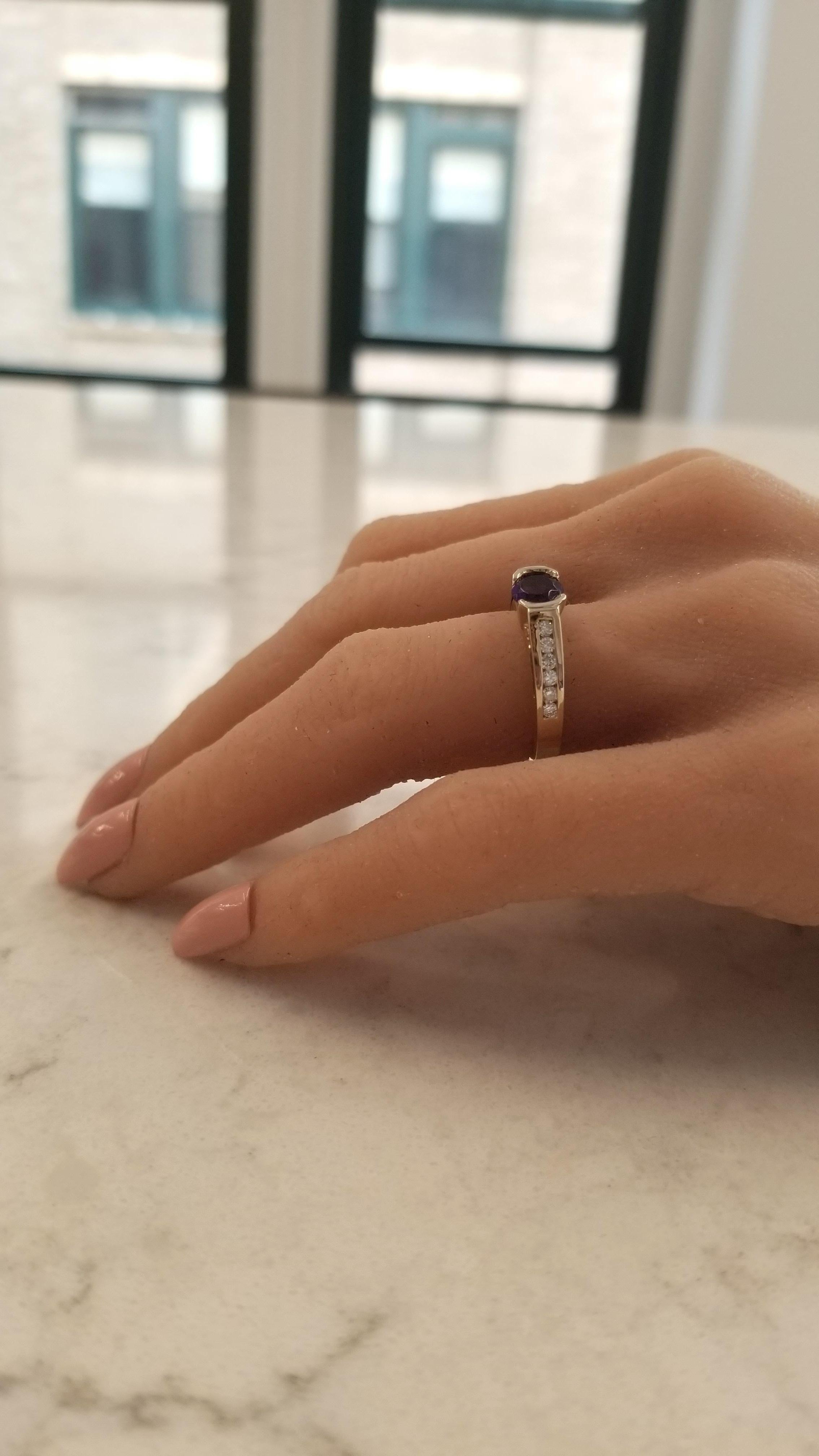 This gorgeous brightly polished platinum and 14 karat yellow gold engagement birthstone ring features one round cut deep, rich purple amethyst set in a half-bezel with a weight of 1 carat. Sparkling round brilliant cut diamonds adorn the sides of