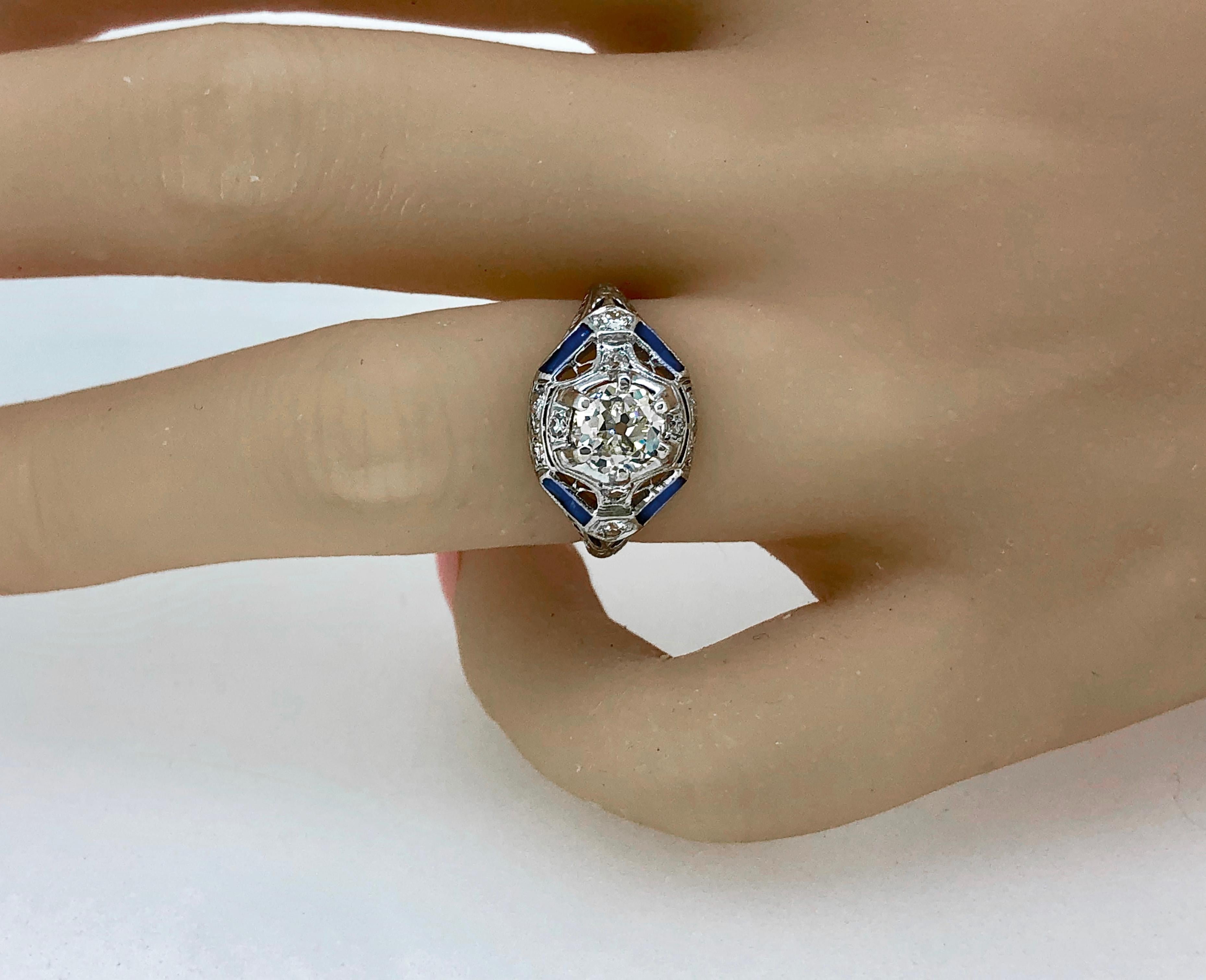 An Art Deco platinum & diamond antique engagement ring featuring a 1.00ct. apx. center diamond of VS1-VS2 clarity and J color. The center diamond is accented with .20ct. apx. T.W. of diamond melee and .80ct. apx. T.W. of synthetic sapphires