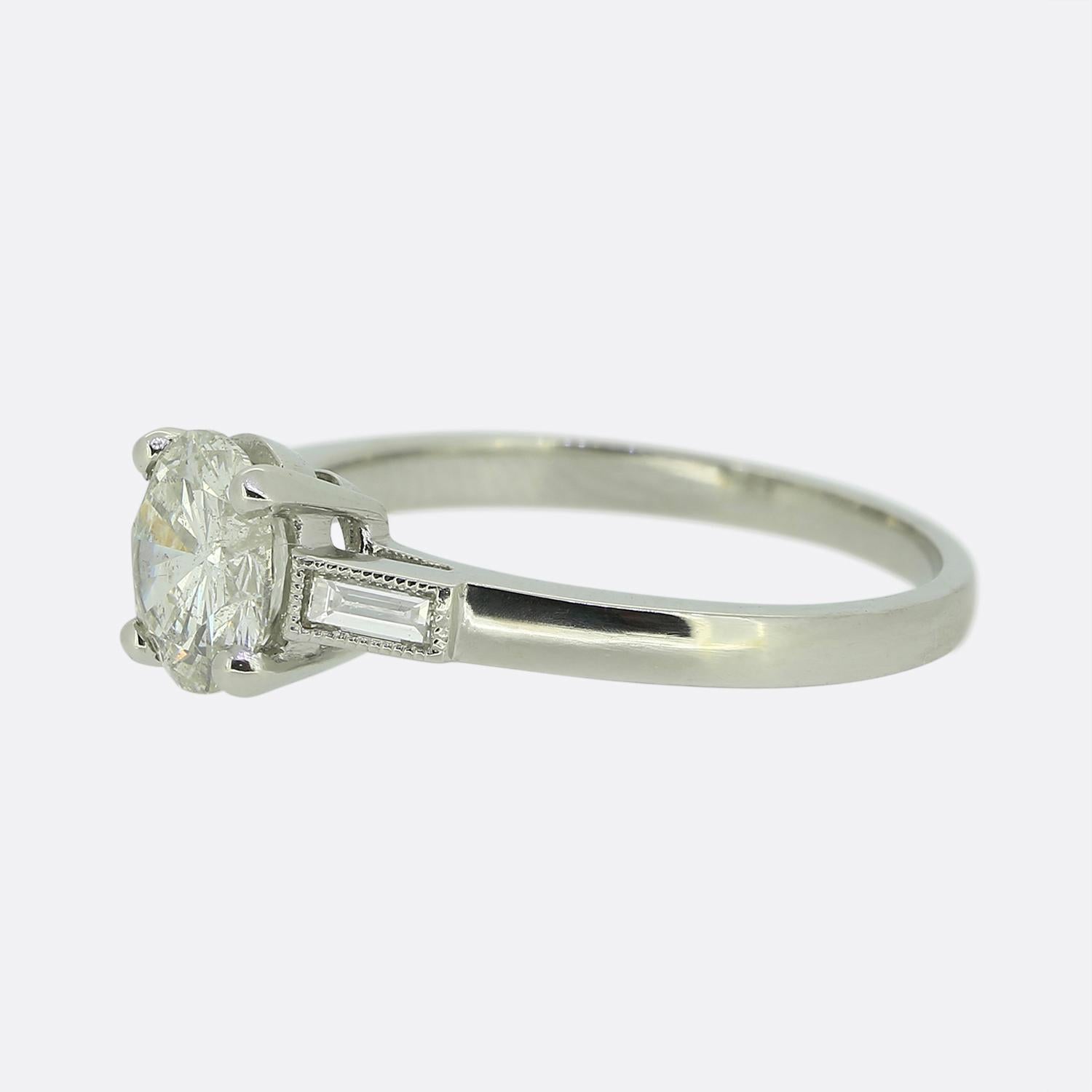 Here we have a charming engagement ring. The ring has been crafted from platinum and showcases a single 1.00 carat round brilliant cut diamond at its centre. This primary stone is set in a secure four-claw setting whilst being flanked by a single
