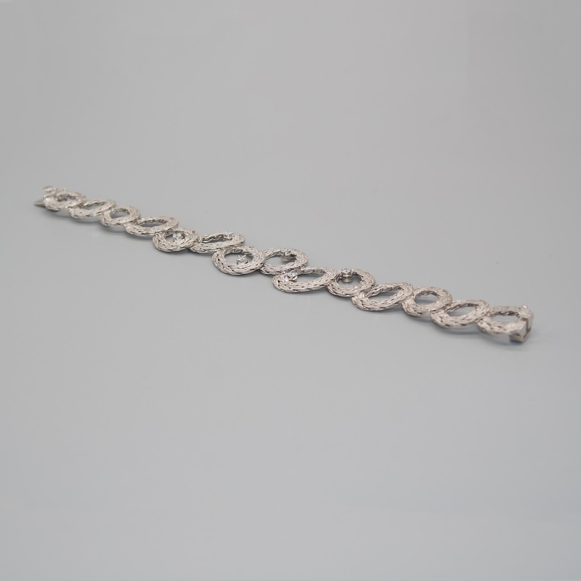 18 karat white gold link bracelet with 6 prong-set diamonds.

Each element appears to be made from a chain with a spectacular mat finish on top and perfectly polished in the back. The superposition of each element in a creative pattern gives a