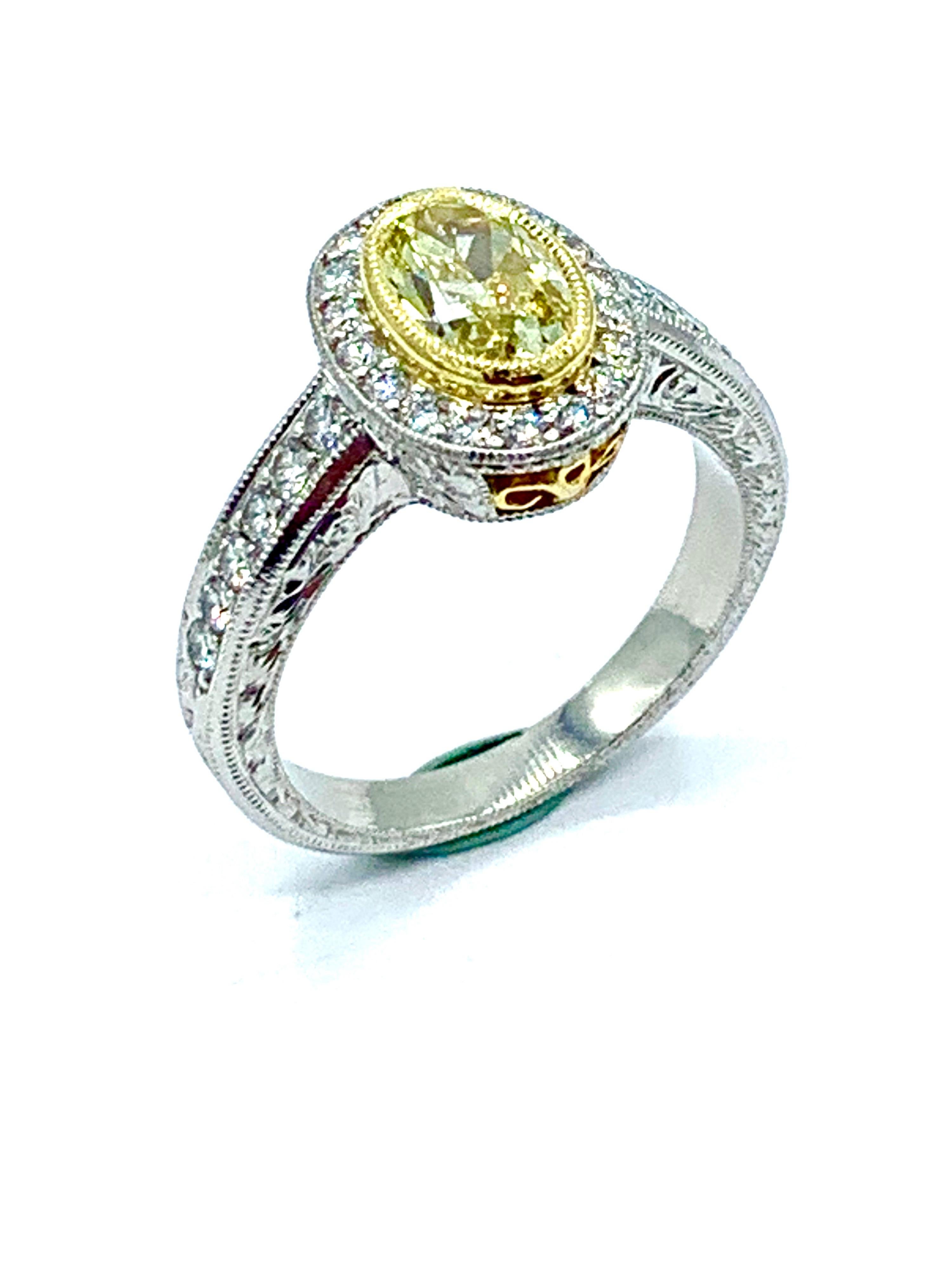 A stunning handcrafted 1.00 carat fancy yellow oval Diamond engagement ring.  The oval is bezel set in 18K yellow gold, surrounded by a single row of round brilliant white Diamonds set in platinum, with a Diamond platinum half shank.  The gallery of