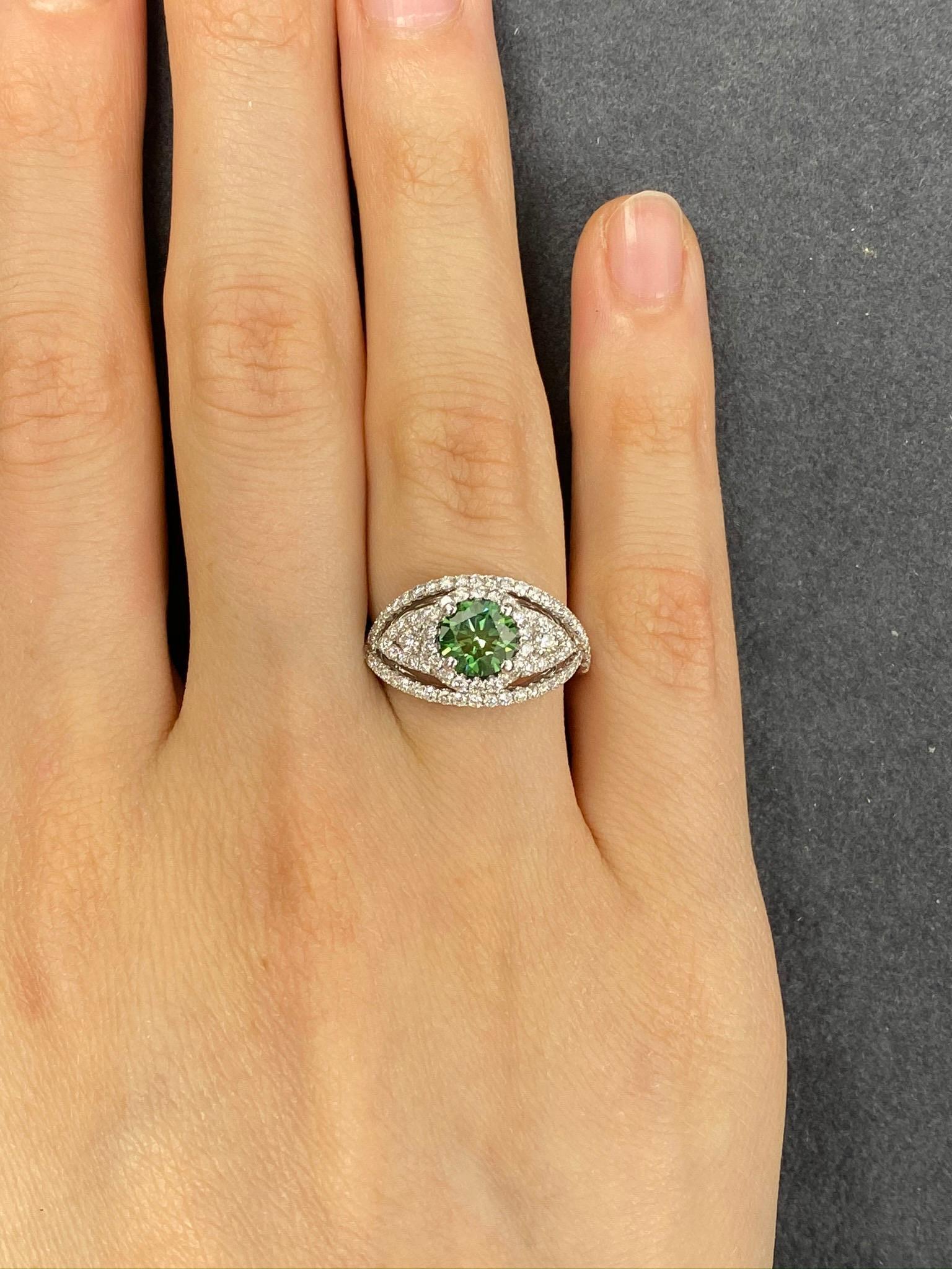 This beautiful cocktail ring features a 1.00 Carat Round Green Diamond surrounded by radiant white diamonds, forming the image of an eye. The Diamond sits on a Diamond Shank and is set in 18k White Gold. Total Diamond Weight (not including center