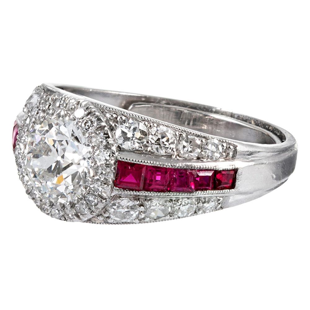 Art deco styling made several decades later… this ring is mounted in platinum and contains one major old European cut diamond at its center. A single line of French cut rubies flanks the center stone, while additional diamonds encircle the