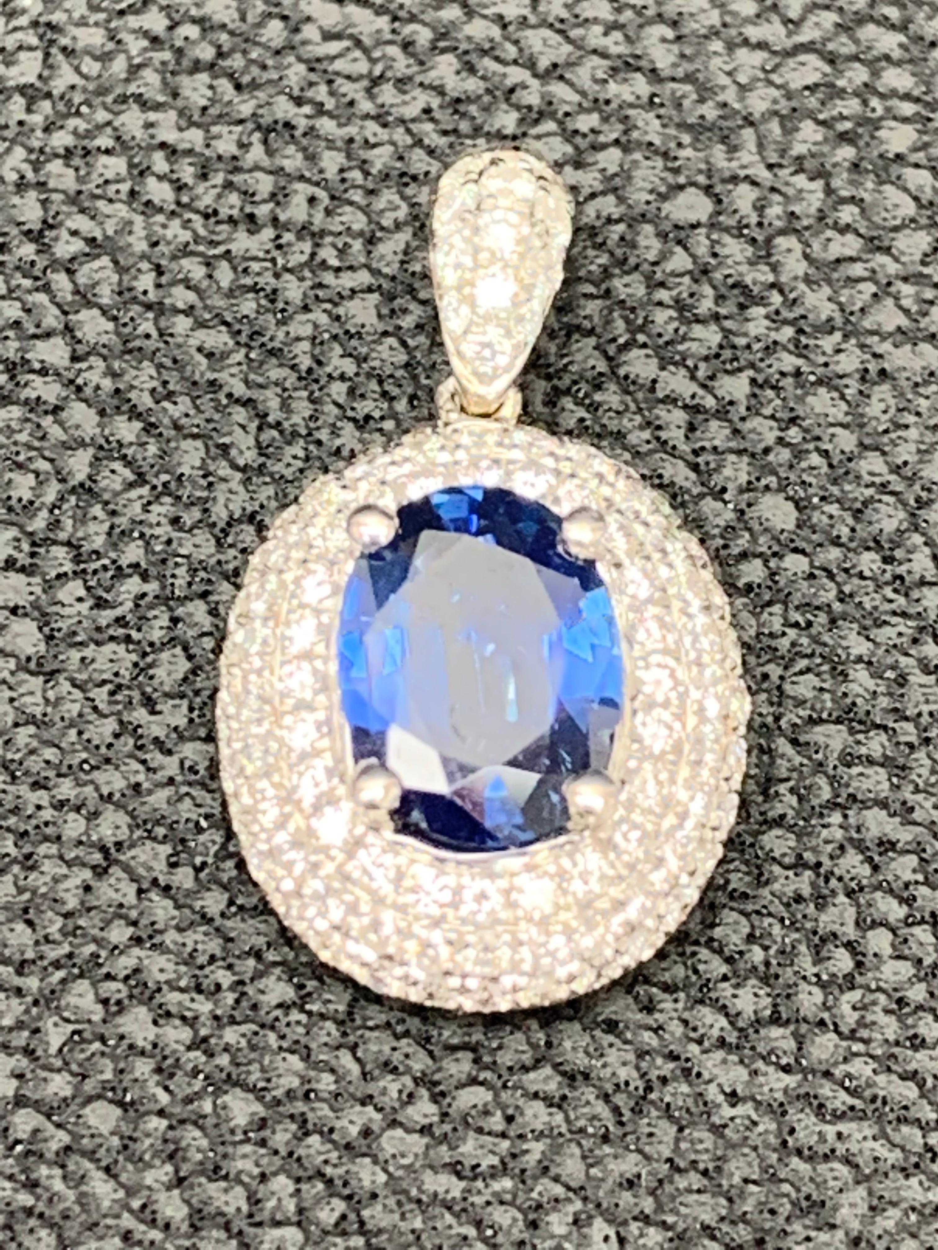 A simple and timeless piece of jewelry showcasing a 1.00 carat oval cut blue sapphire, set in a brilliant diamond halo made in 18k white gold. Diamonds weigh 0.48 carats total. 18