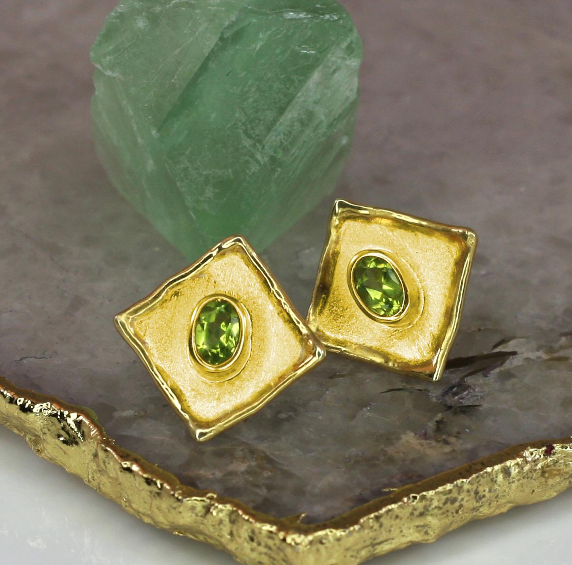 These small diamond shape Yianni Creations Earrings are 100% Handmade from 18 Karat Yellow Gold. Each earring features each 0.50 Carat Oval Cut Peridot. The unique look is created by the brushed texture and nature-inspired liquid edges. Contact us