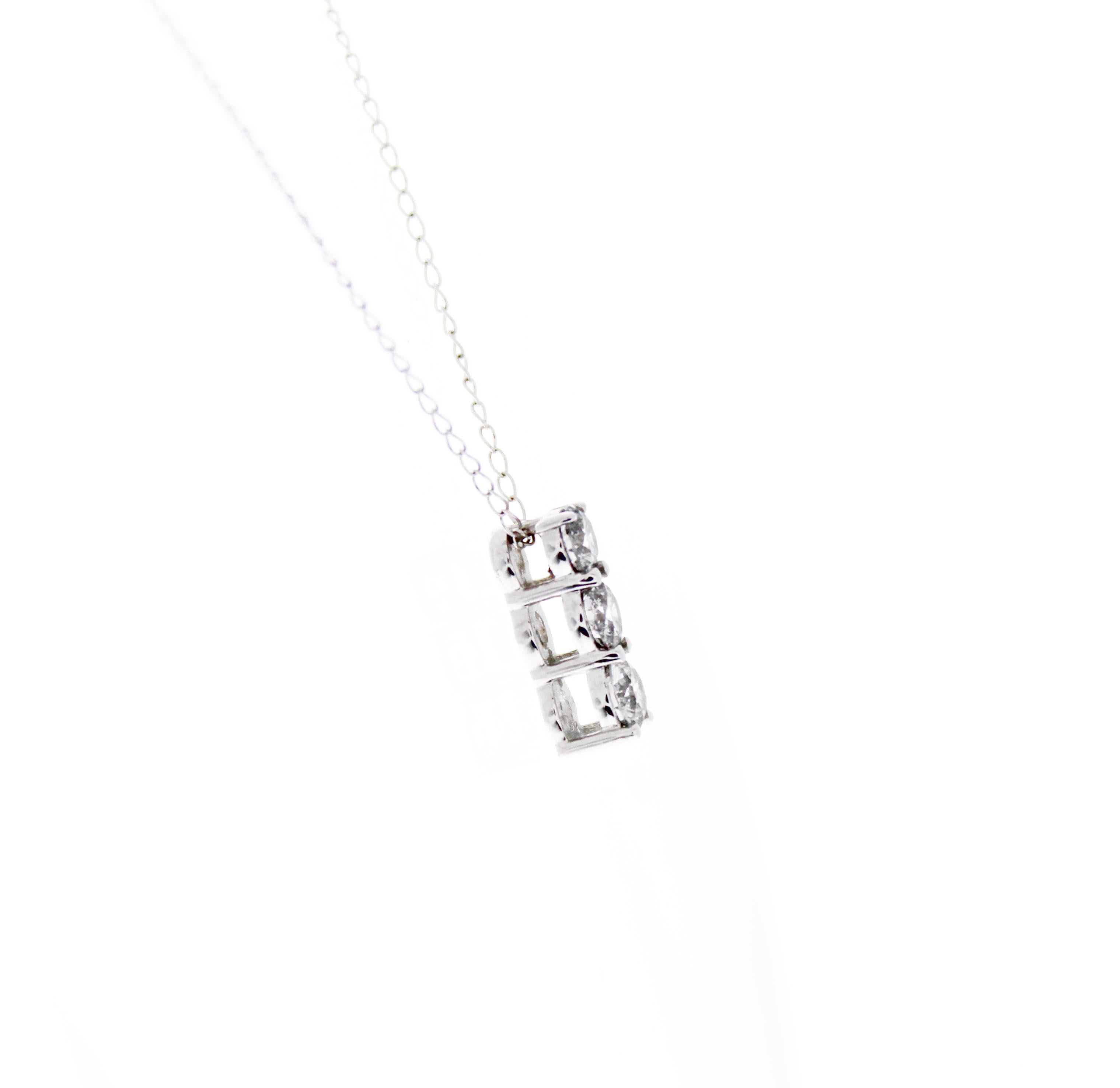 This impressive three-stone round diamond pendant is finely crafted in brightly polished 14 karat white gold and features three stones totaling a carat weight of 1.00CTW. These diamonds are I1 clarity. Ideal as an anniversary or birthday present,