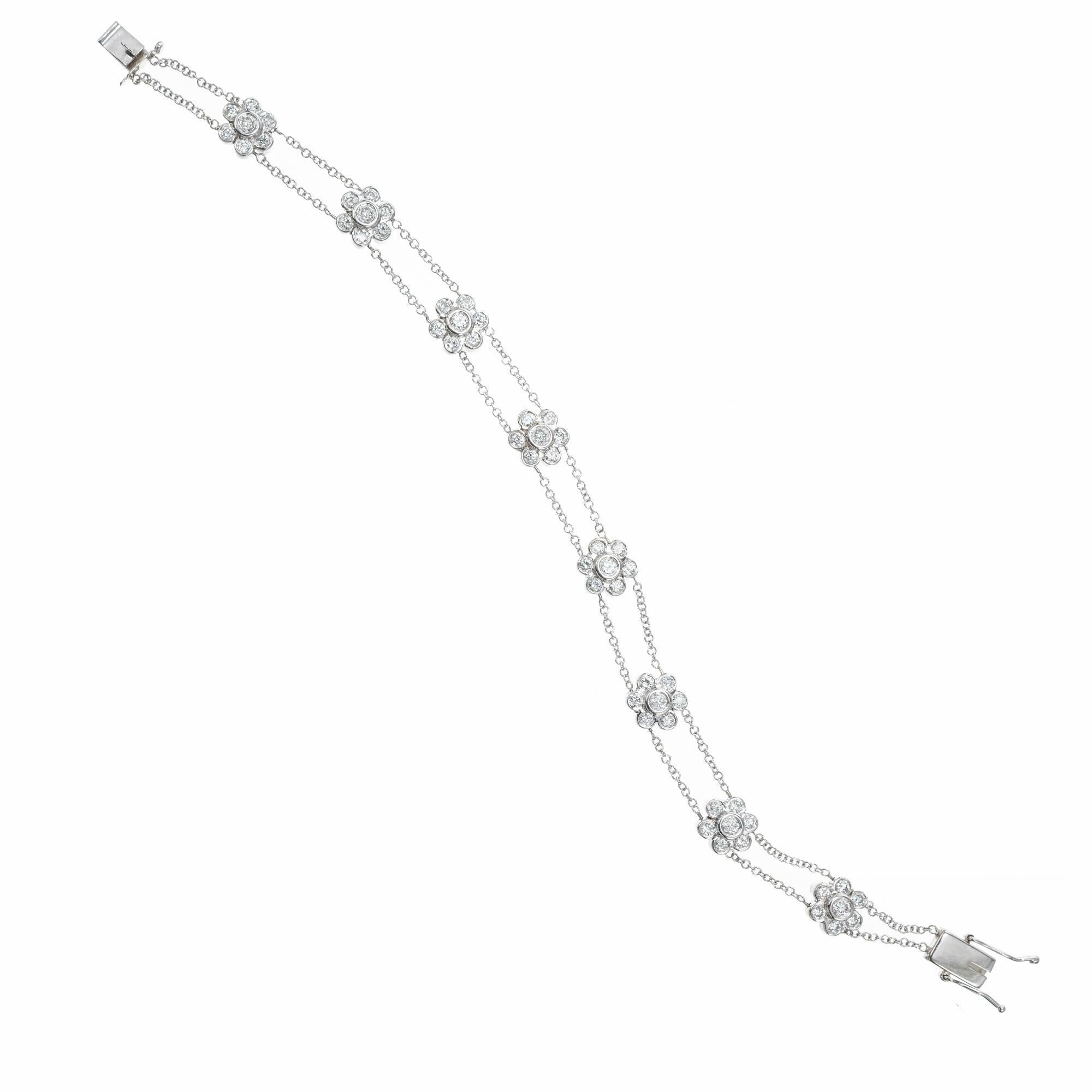 Double chain 8 station diamond flower cluster bracelet. 56 round bezel set diamonds in 8 flower settings connected by a double chain bracelet. Box catch with two safety's. 7 inches long.

56 round diamonds, H-I VS SI approx. 1.00cts
14k white gold