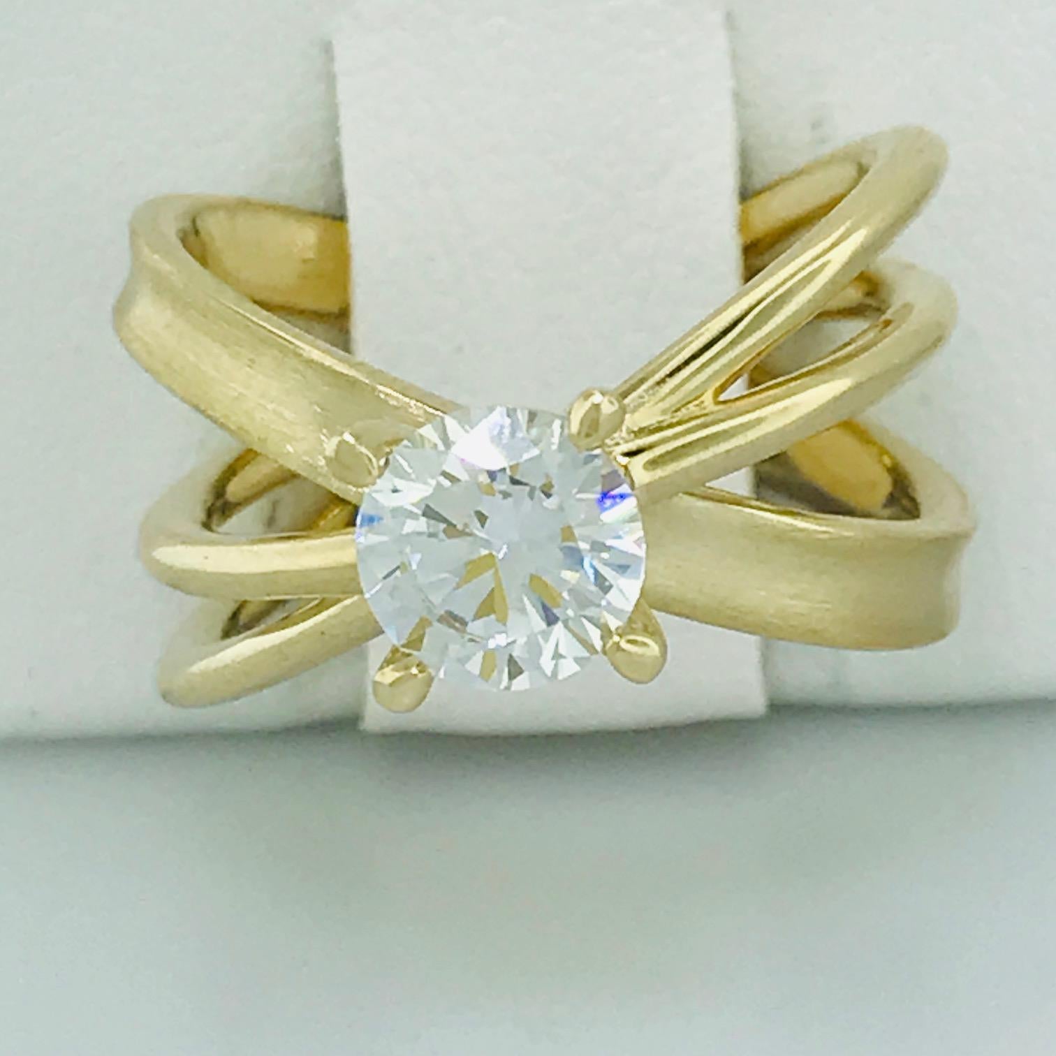 Un anillo atrevido y único, perfecto para la novia innovadora y elegante. Este anillo X es un anillo de compromiso de moda con una mezcla de alto pulido y acabado satinado. Esta montura se hizo para sujetar una piedra redonda de 6,5 mm (diamante de