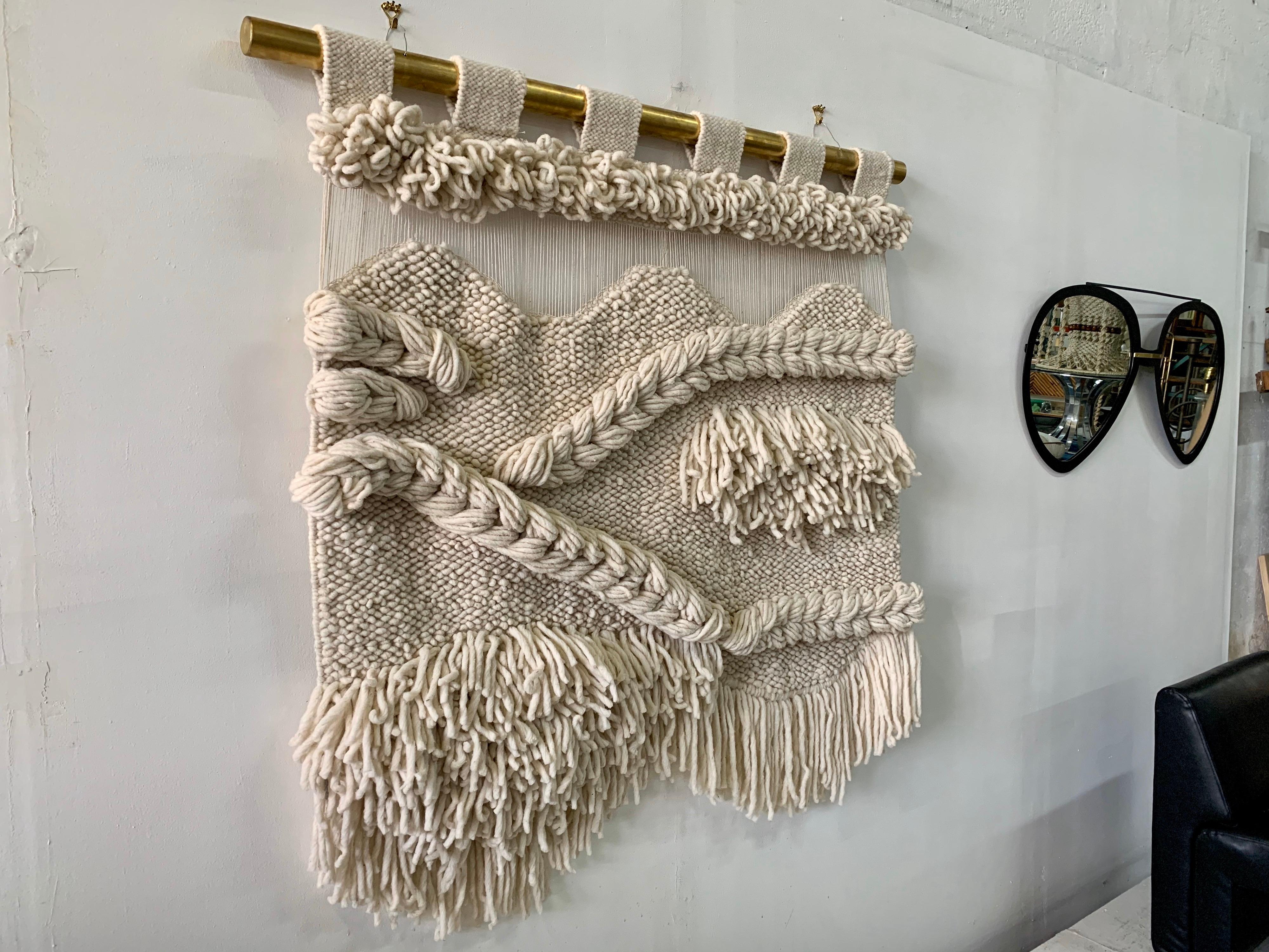All natural tapestry in non-died wool textile, woven by hand in this intricate and elegant design. The brass hanging rod has been custom designed for this piece for the best possible displaying and hanging. Details include a delicate string design