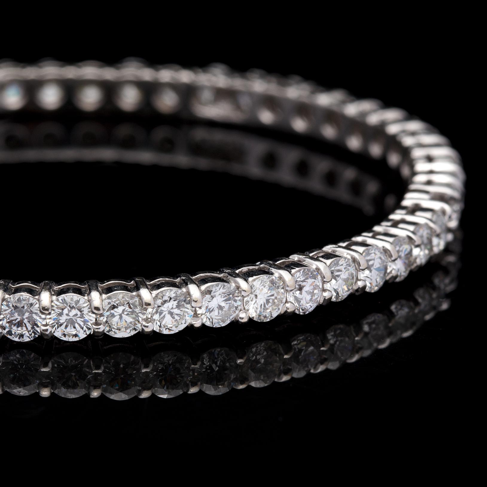 The perfect way to add sparkle to any wrist! This impressive diamond eternity bangle features 51 exceptionally well matched round brilliant diamonds delicately set in 14 karat white gold. With a total diamond weight of approximately 10 carats, this