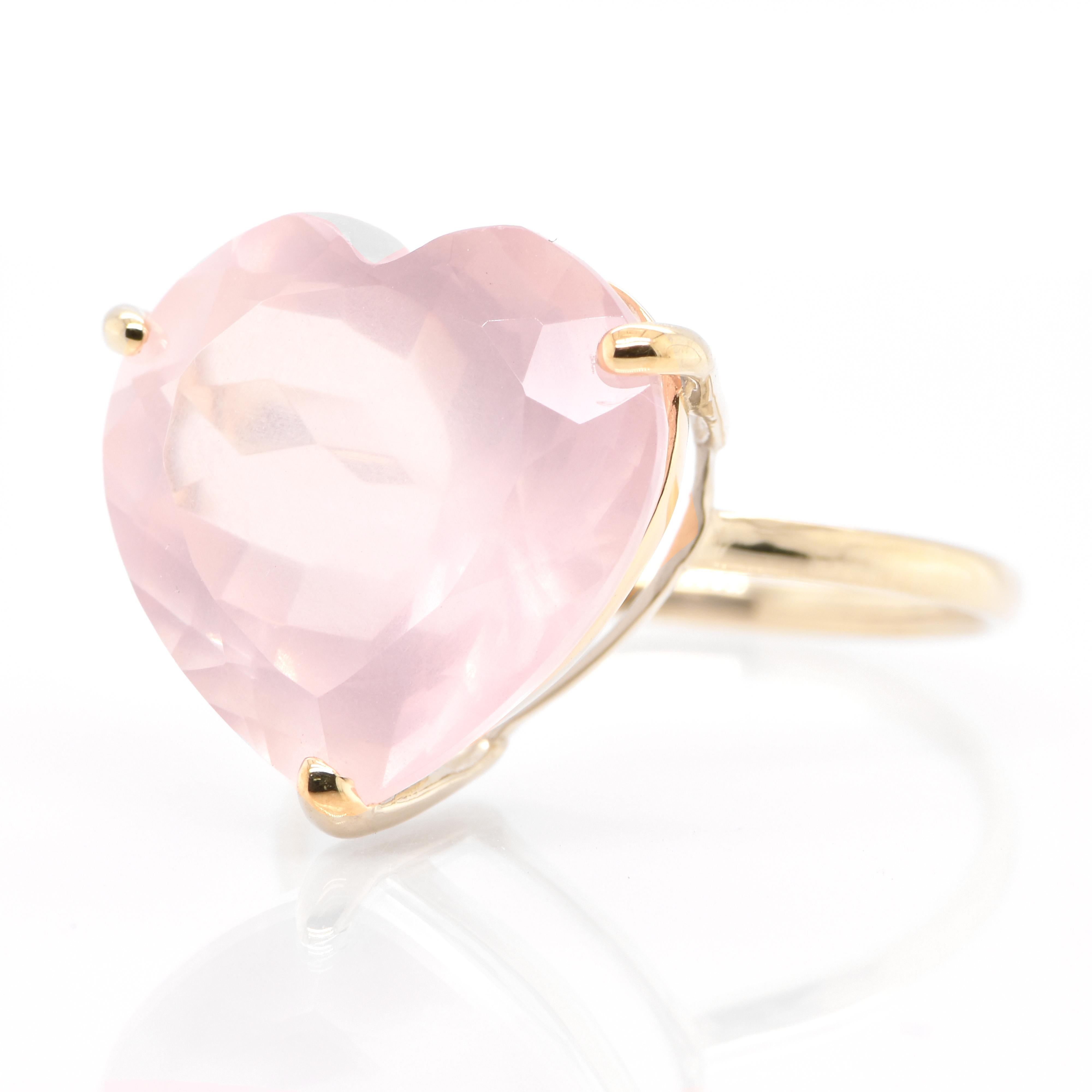 A beautiful Cocktail Ring featuring a 10.00 Carat, Natural Heart-Cut Rose Quartz set in 18 Karat Yellow Gold. Rose quartz gets its name from its delicate pastel pink color. Rose Quartz often features internal fractures that give it a cloudy
