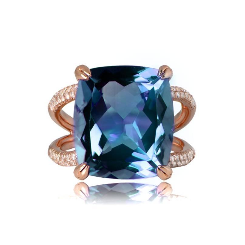 A stunning 14k rose gold ring highlights a central cushion-cut blue topaz, boasting a weight of around 10 carats. Flanking the prong-set center stone are rows of round brilliant cut diamonds, totaling approximately 0.60 carats, elegantly adorning