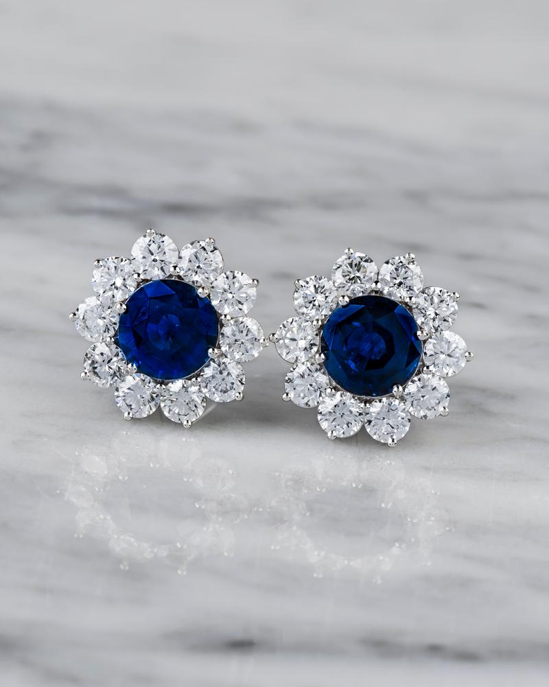 10.01 Carat blue sapphire surrounded with 8.3 carat total weight in round diamonds,  earrings are set in 18k white gold. 
Diamond quality F-G color, VS2-SI2 clarity, 20 diamonds total.
Sapphire measurements: 10.3mm 
