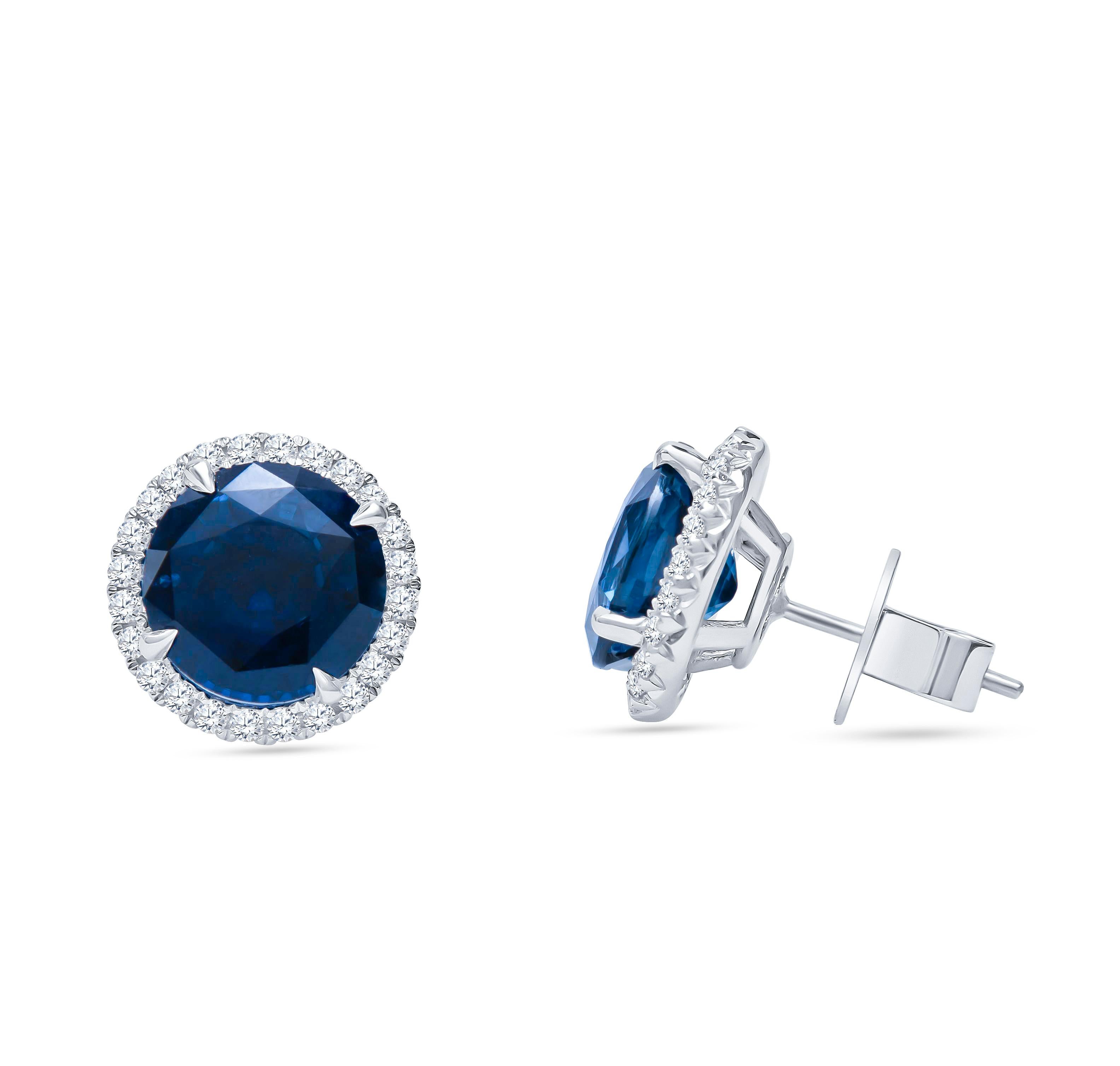 18K white gold round halo stud earrings featuring 10.01 carats total weight in two round natural blue sapphires and 0.64 carats total of round brilliant cut diamonds. These gorgeous earrings are custom made in our workshop here in Houston and are of