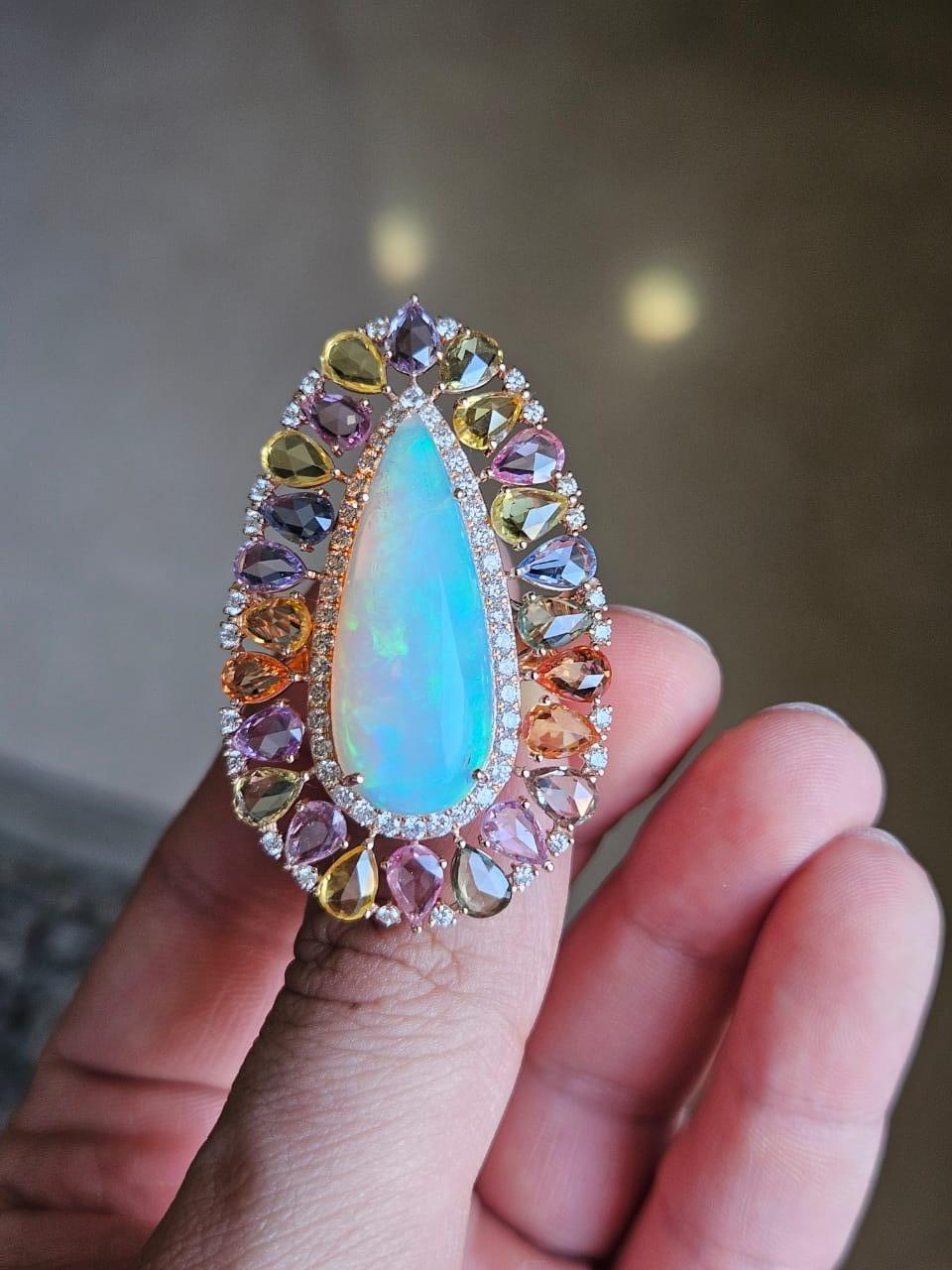 A very gorgeous and beautiful, one of a kind, Opal & Multi Sapphires Cocktail Ring set in 18K Gold & Diamonds. The weight of the pear shaped Opal Cabochon is 10.05 carats. The Opal cabochon is of Ethiopian origin. The weight of the Multi Sapphires