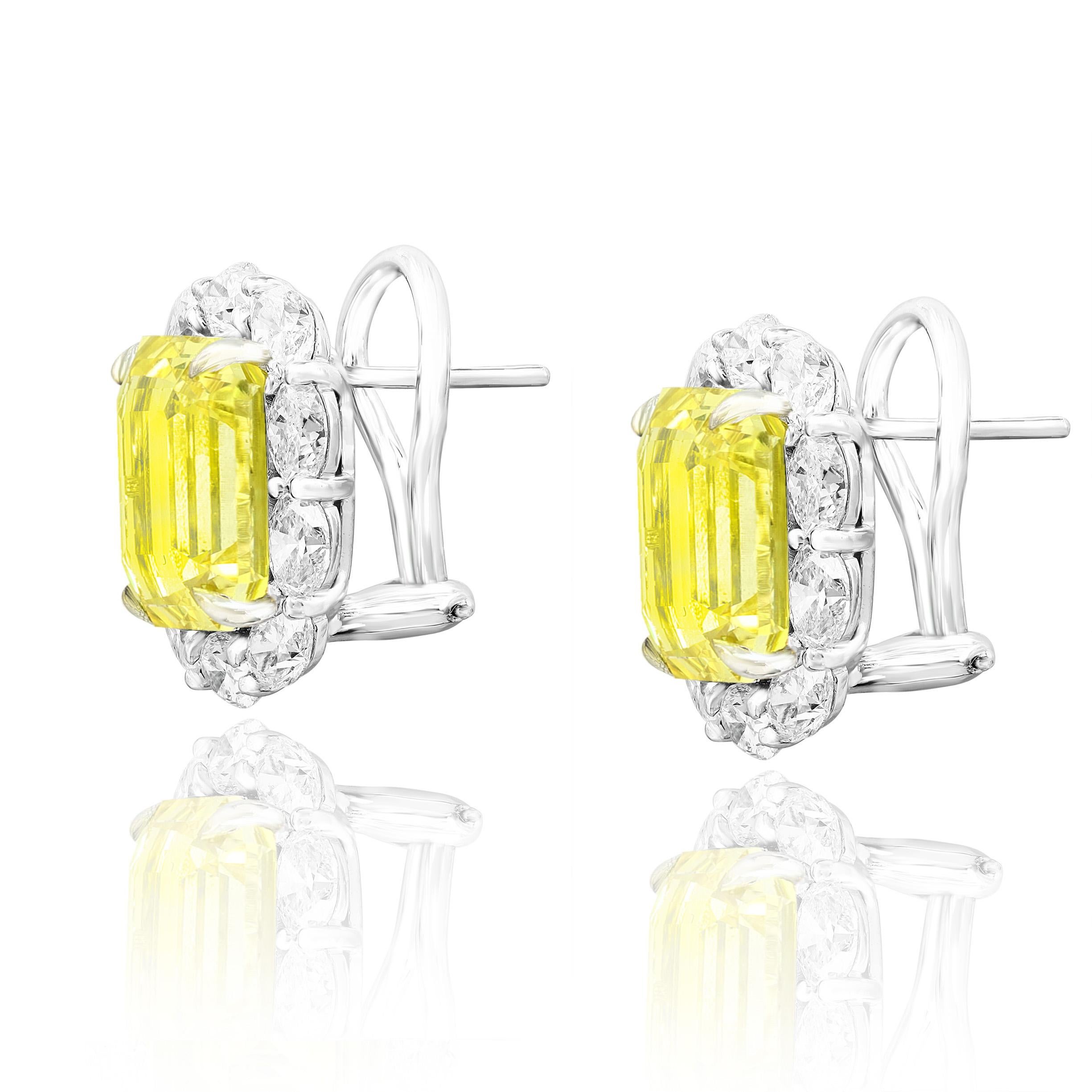 Showcasing two color-rich Emerald cut Yellow Sapphires weighing 10.09 carats total, surrounded by a single row of oval-cut brilliant diamonds. 20 Accent diamonds weigh 3.18 carats in total. Set in 18 karats white gold. Omega Clip with the