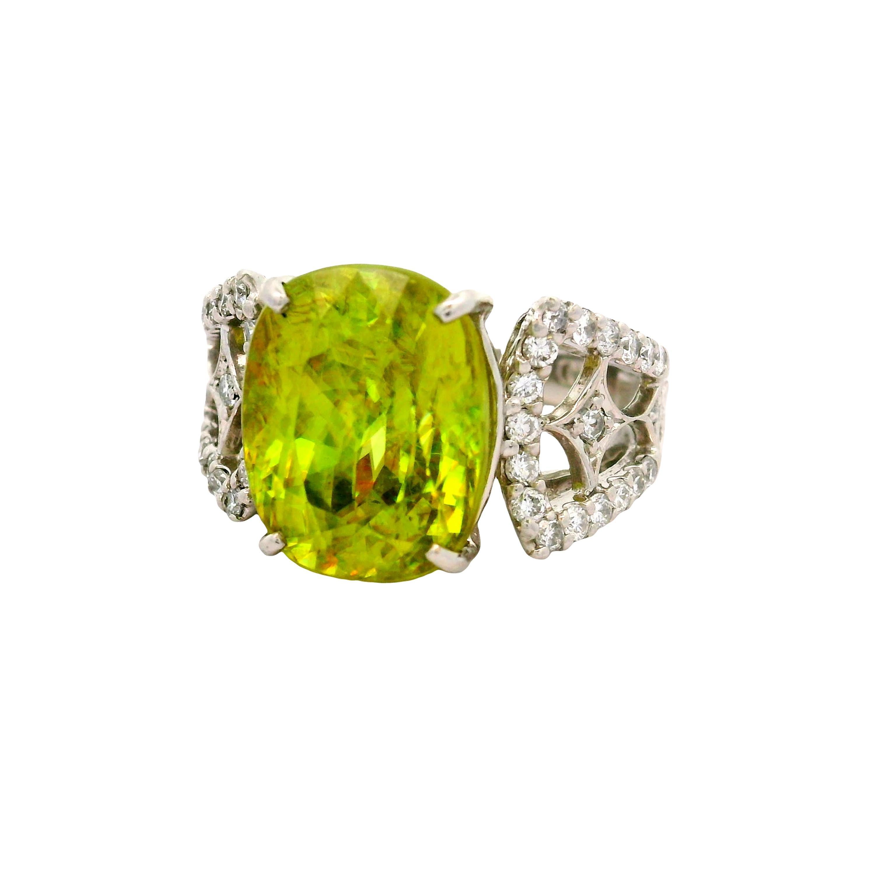 Una exquisita Esfena en forma de cojín, de 10,09 quilates, llama la atención por su vibrante tono verde y su exquisito fuego y brillo. Se pueden ver brillantes e intensos destellos de color danzando dentro de la piedra. El Sphene se complementa con